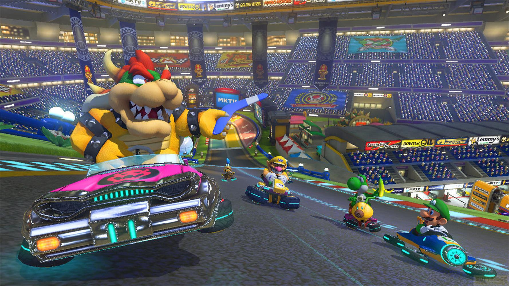 Bowser corre su un kart rosa con altri personaggi di Mario in uno stadio, folla festante.