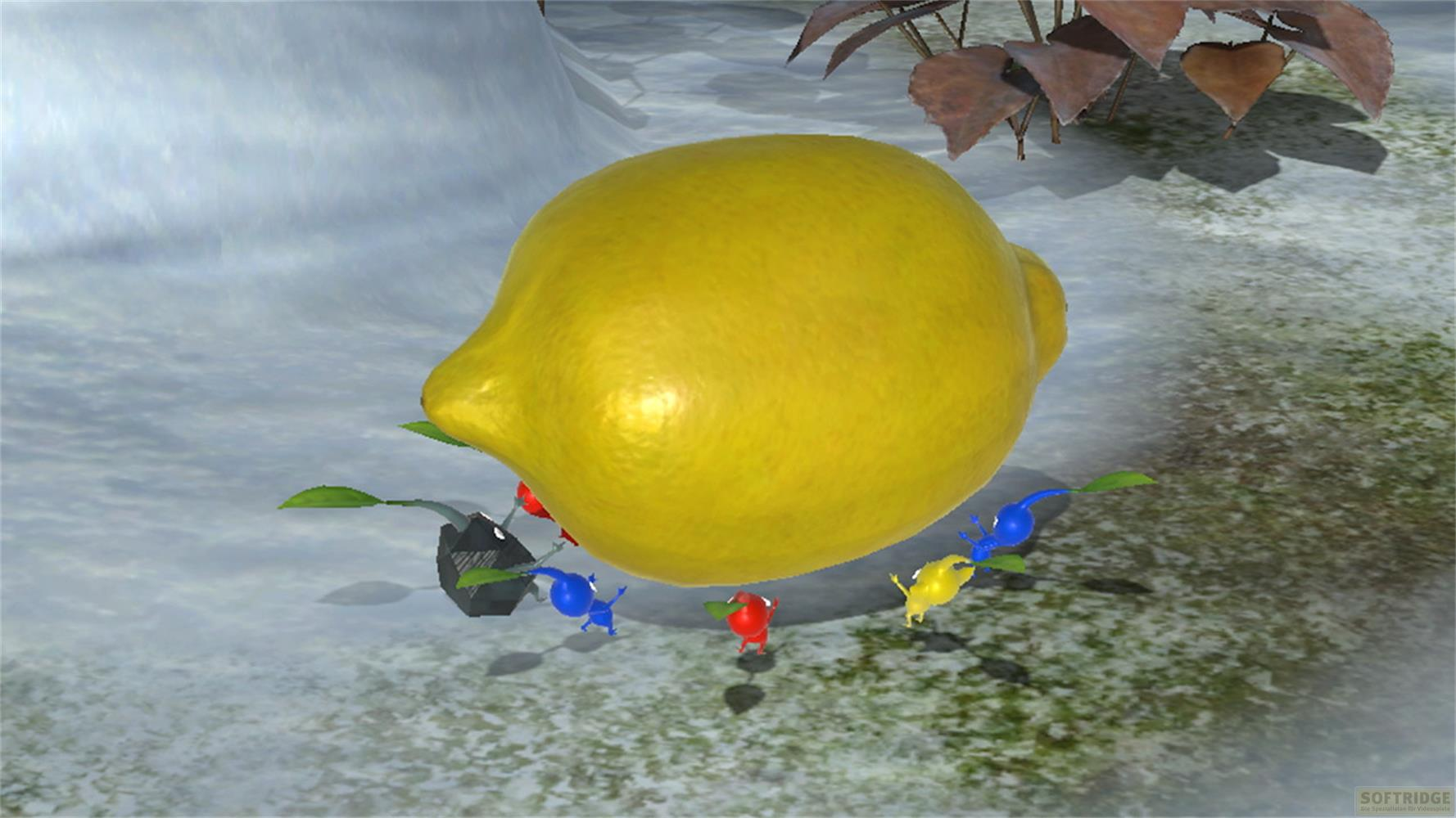 Piccole creature blu, rosse e gialle circondano un grande limone giallo su un terreno roccioso.