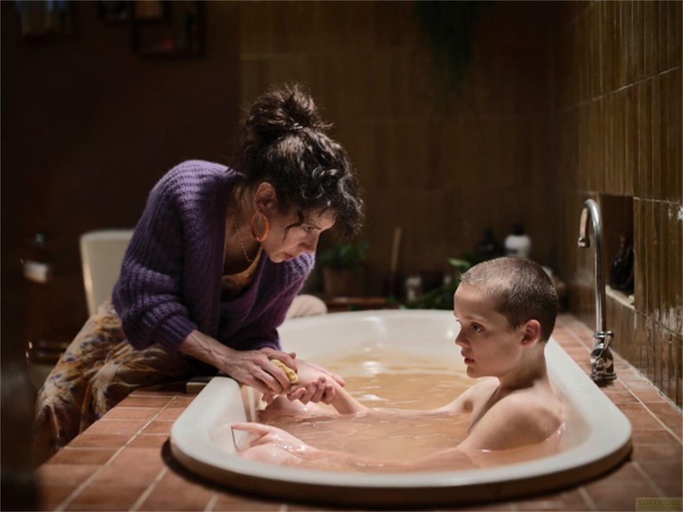 Una donna lava un bambino in una vasca da bagno piena d'acqua marrone.