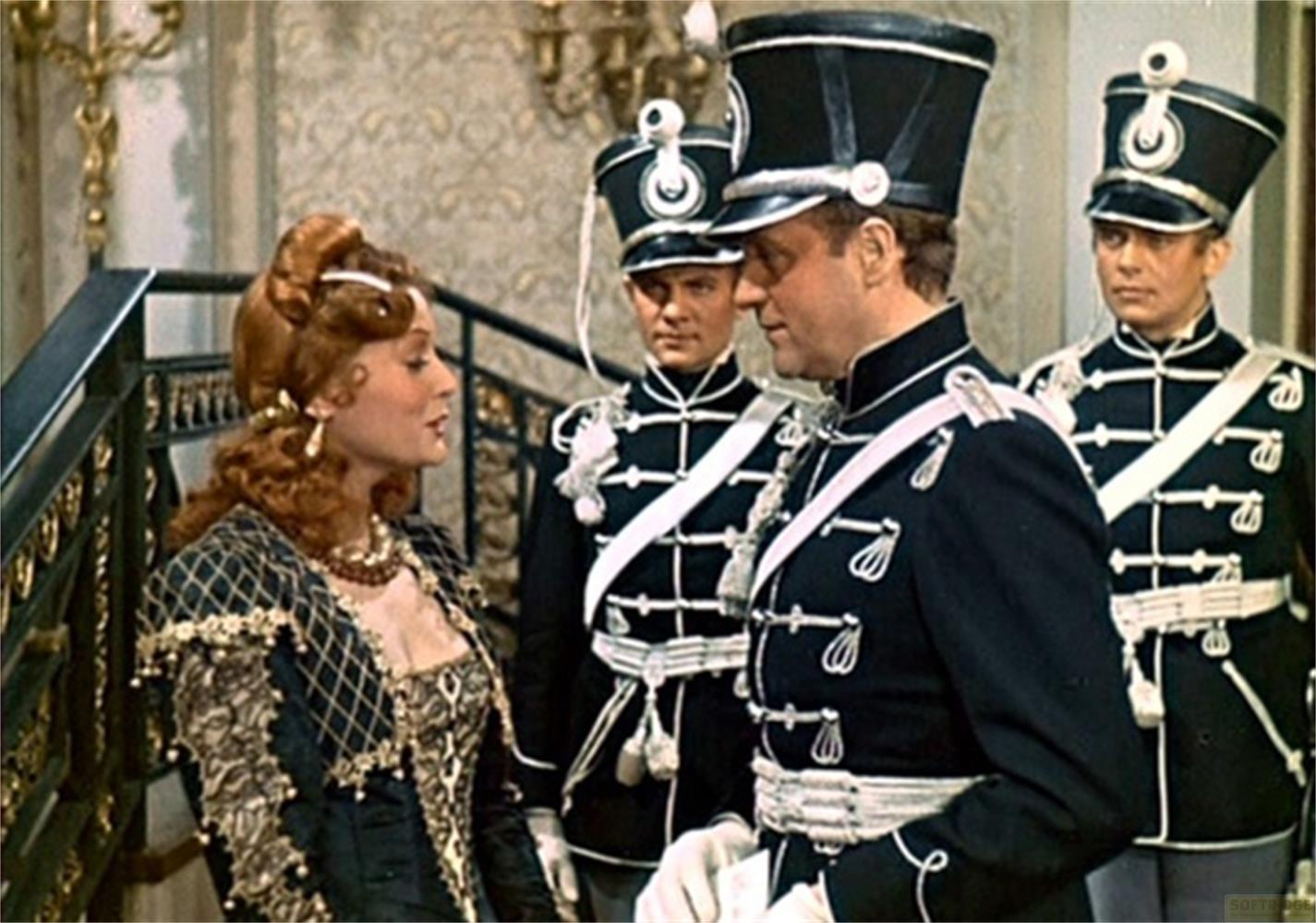 Una donna parla con un uomo in uniforme, due soldati sullo sfondo.