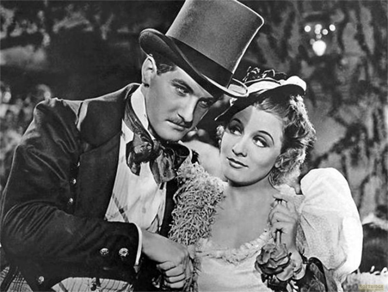 Un uomo con cappello a cilindro e una donna in abiti storici in braccio.