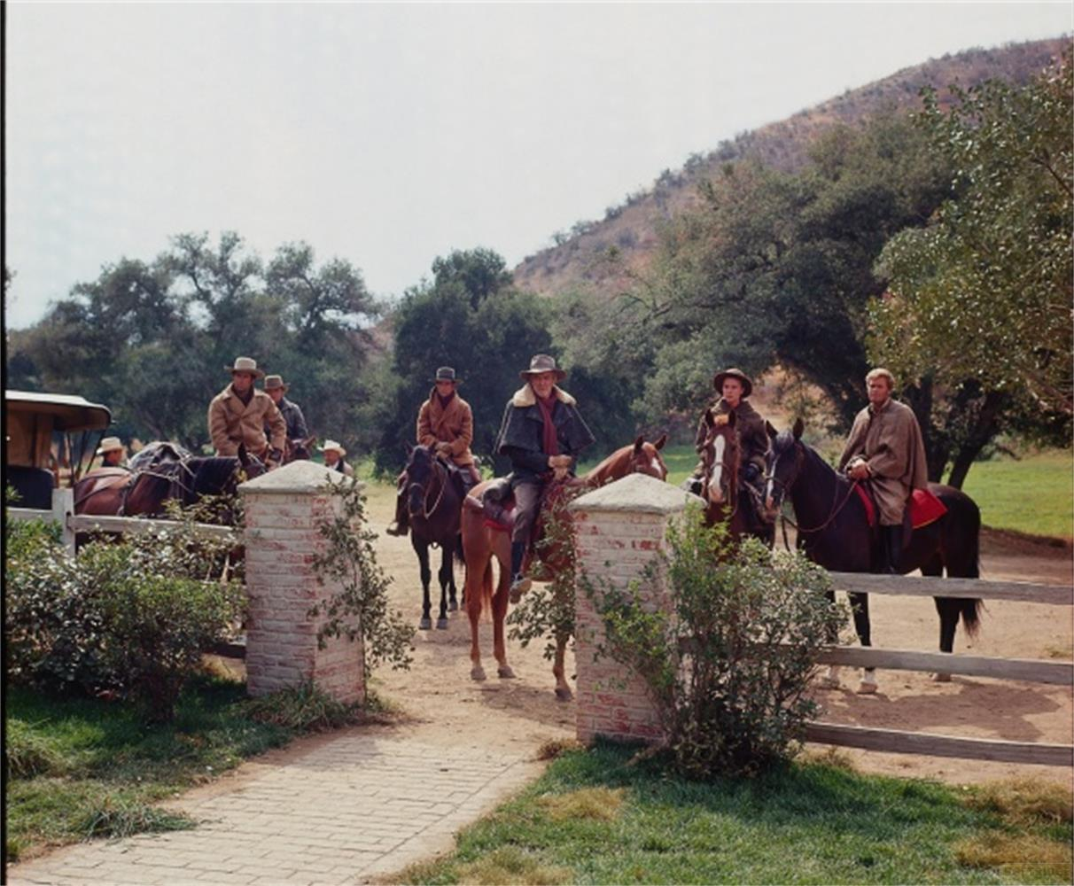 Gruppo di persone a cavallo, con un carro, in un paesaggio rurale.