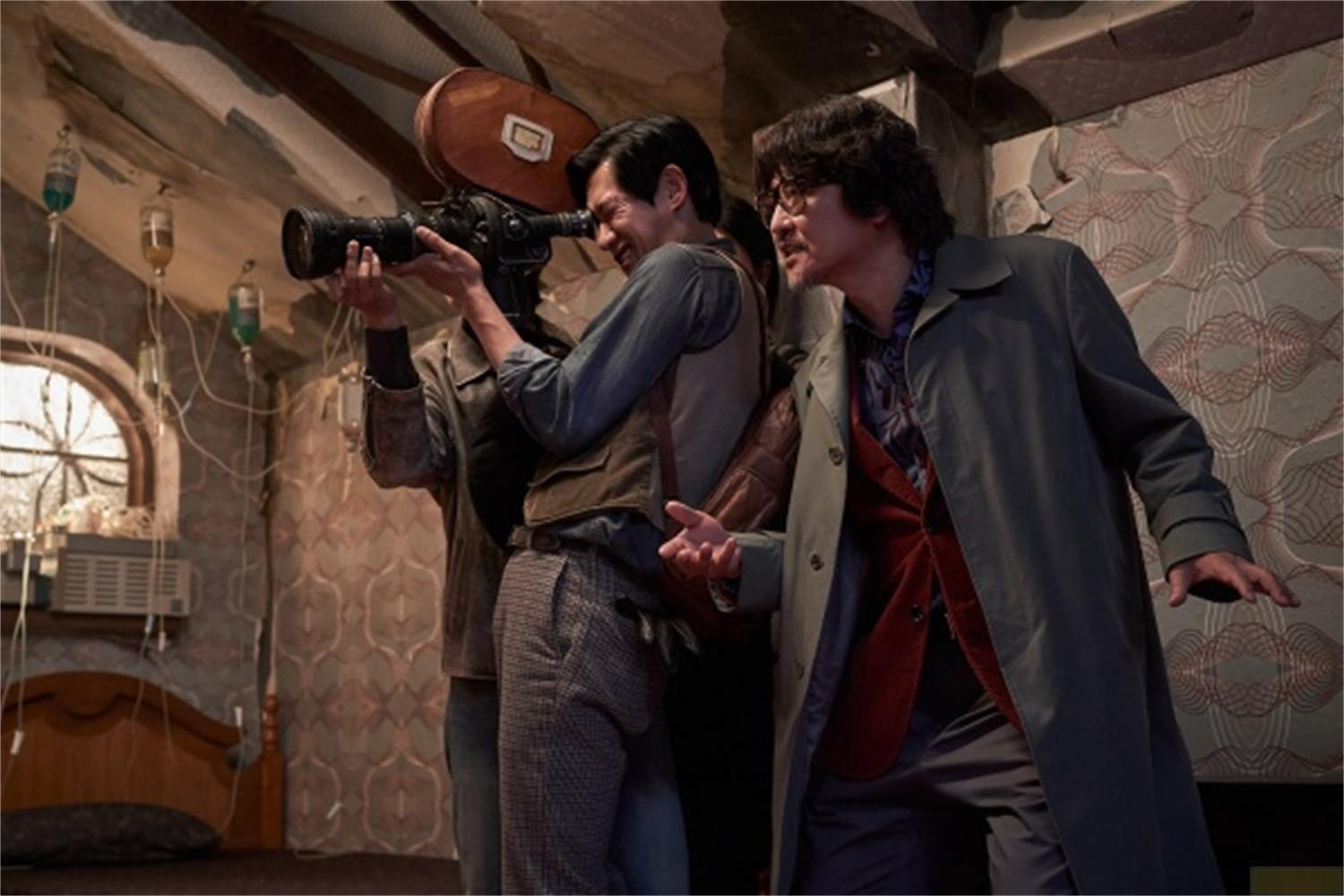 Un uomo filma con una videocamera vintage mentre due uomini sono al suo fianco.