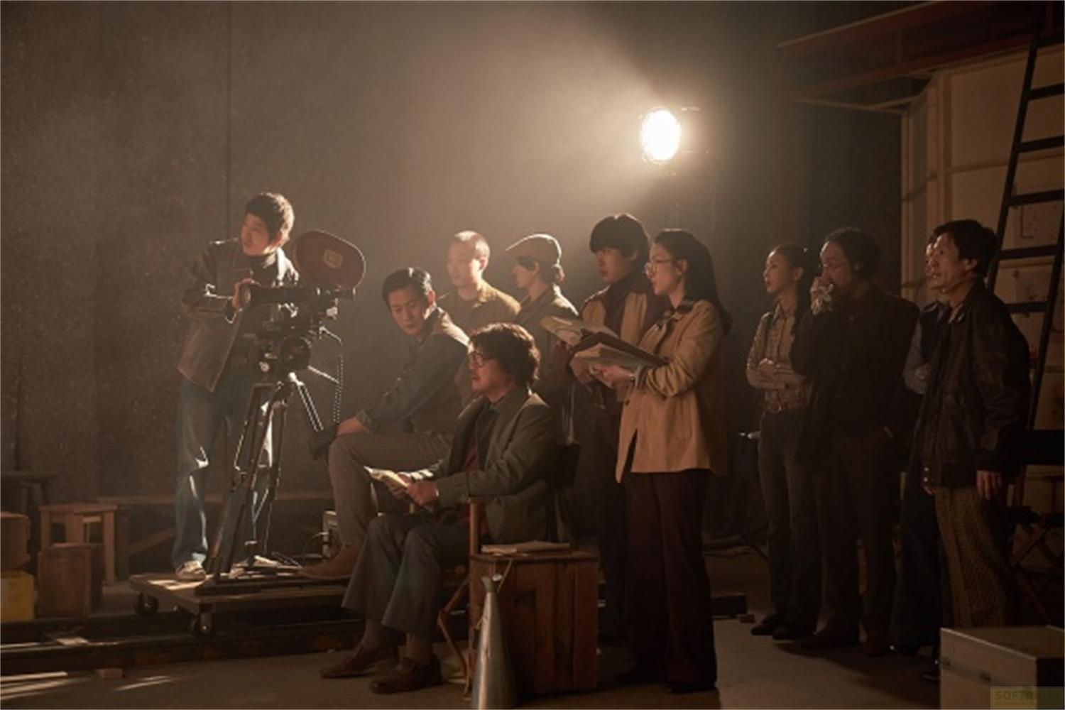 Una troupe cinematografica con una cinepresa su un carrello, illuminata da un faretto.