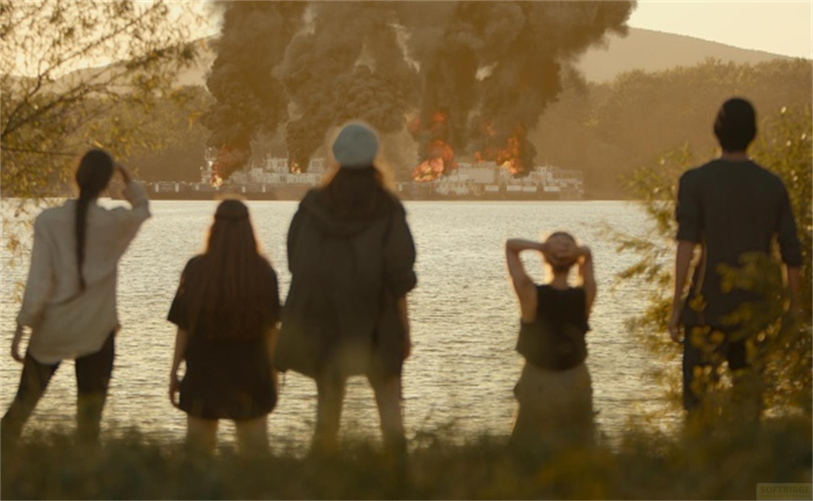 Persone guardano navi bruciare sull'acqua, con fumo e fiamme.