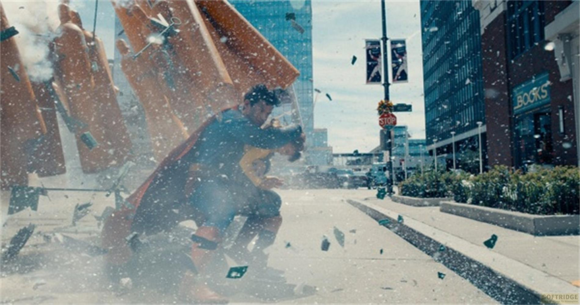 Superman hält einen umfallenden orangefarbenen Gegenstand, Trümmer fliegen.