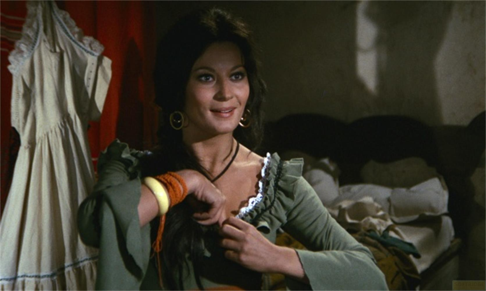 Una donna con capelli scuri e collana d'oro indossa un vestito verde.