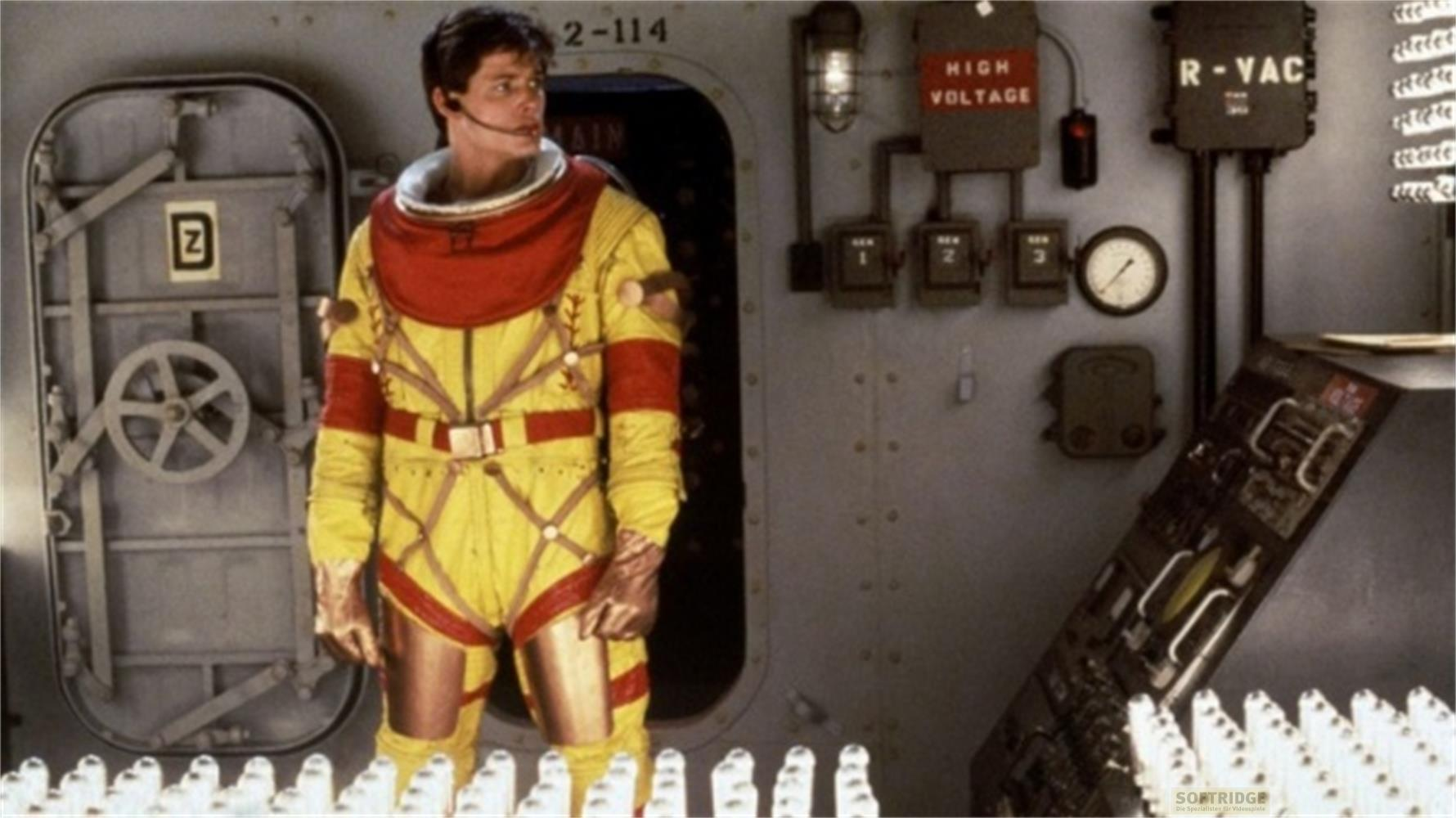 Un uomo in tuta spaziale gialla con colletto rosso è davanti a una porta.