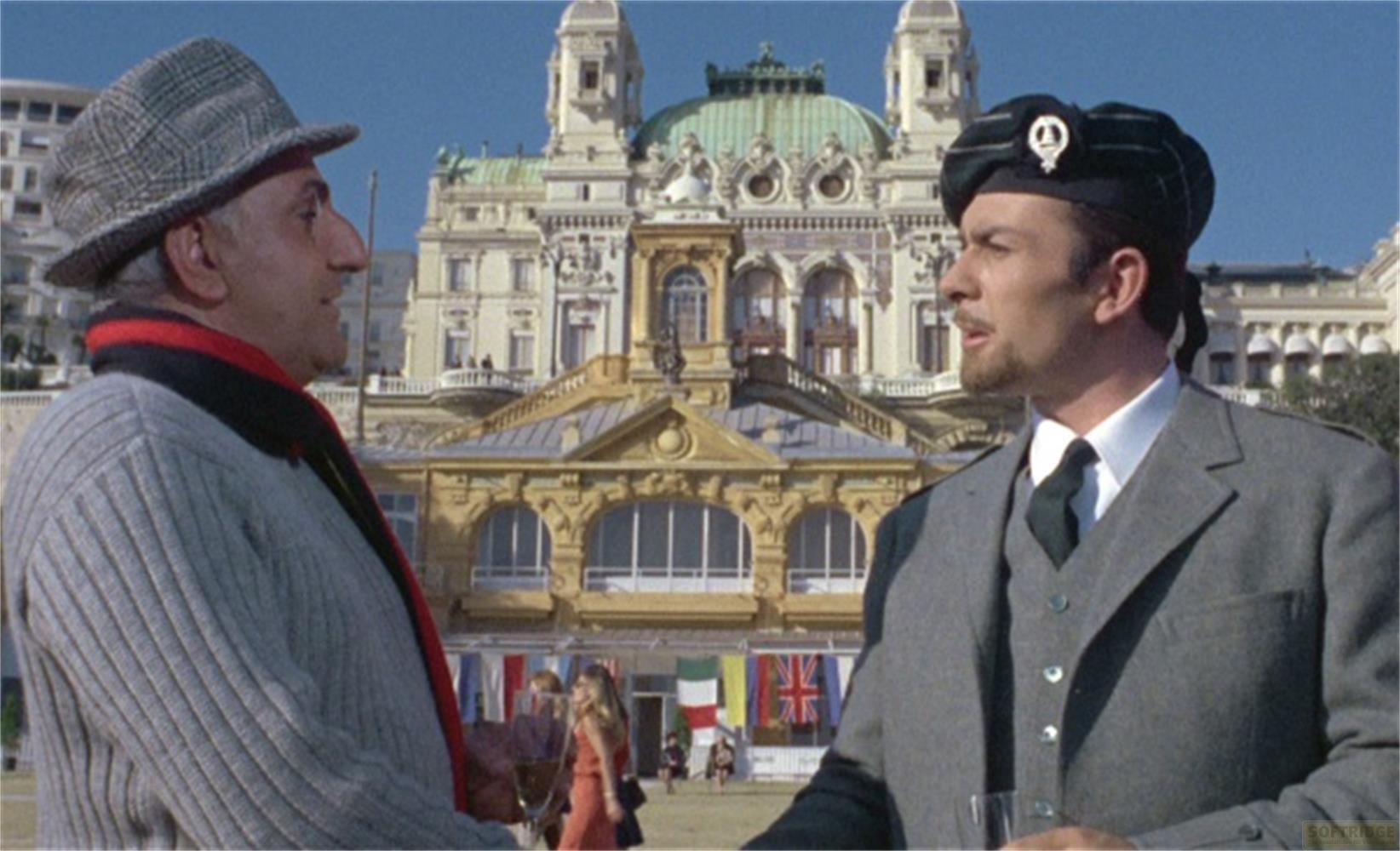 Due uomini davanti a un casinò. Uno indossa un kilt e un berretto. Sventolano bandiere.