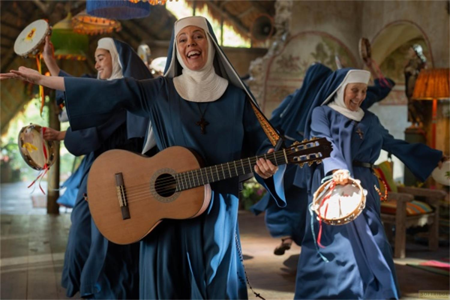 Suore in abiti blu danzano suonando chitarra e tamburelli.