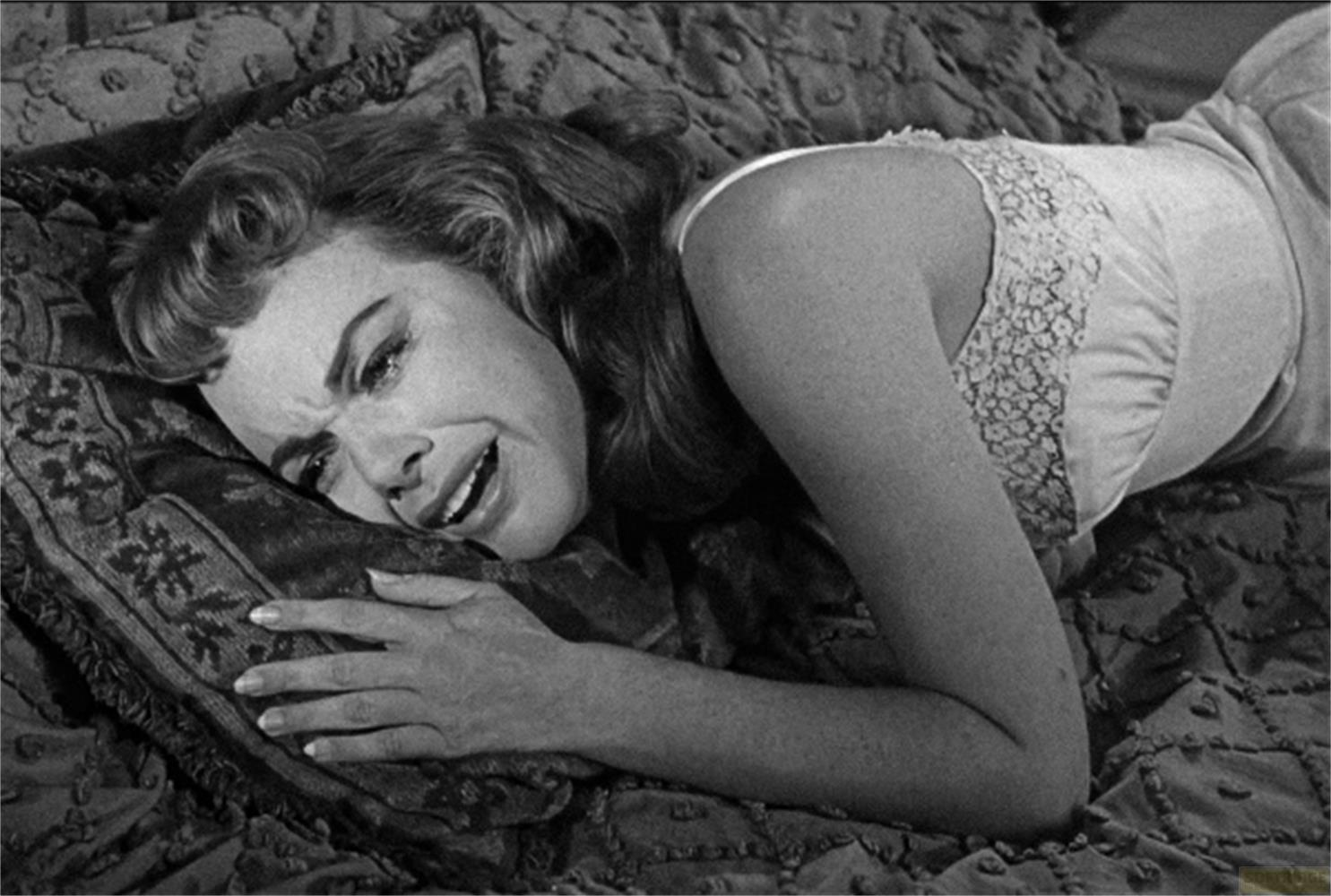 Una donna giace piangendo su un cuscino fantasia su un letto.