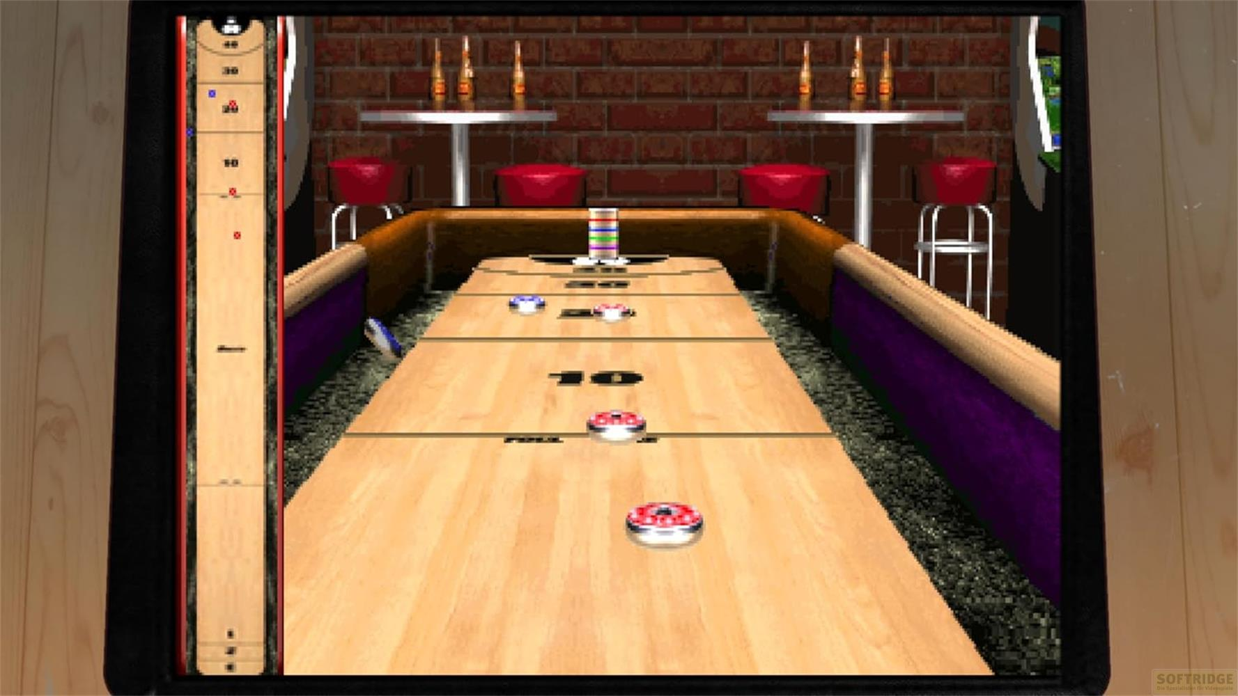 Table de shuffleboard avec palets rouges et bleus, bar en arrière-plan.