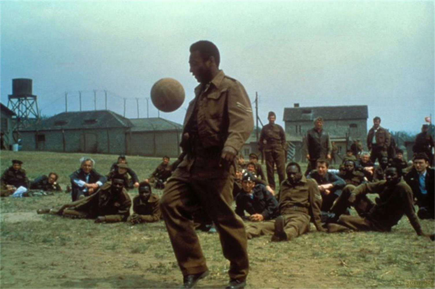 Ein Soldat spielt Fußball, während andere Soldaten zuschaun.
