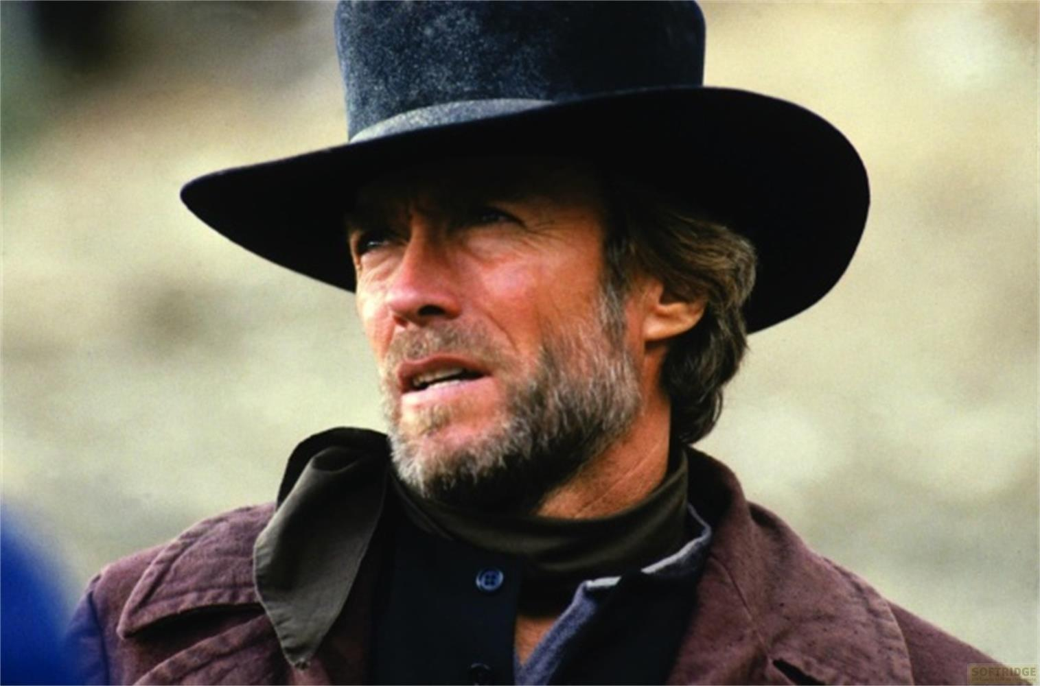 Un uomo con la barba indossa un cappello a cilindro nero e una giacca marrone.