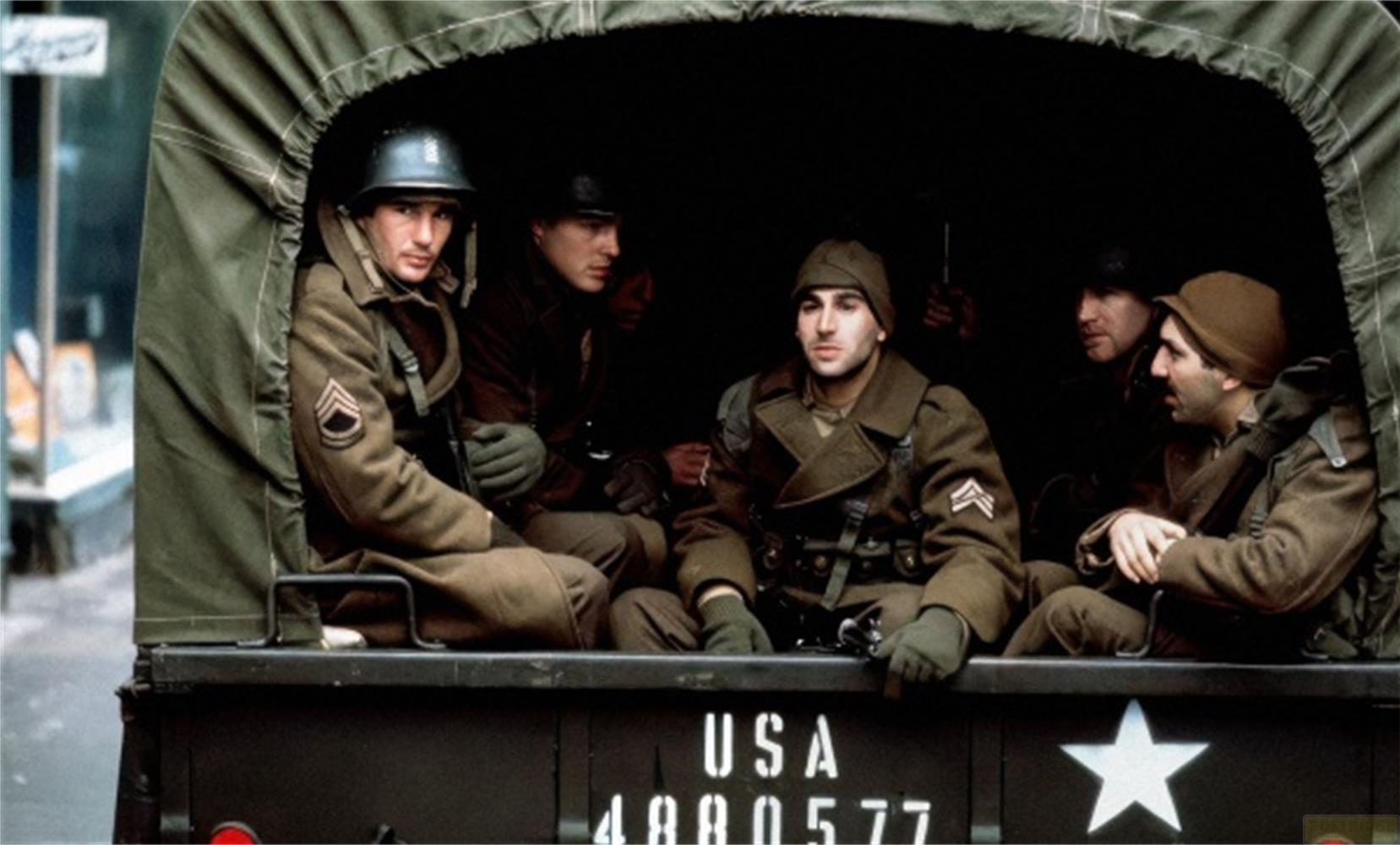 Soldaten in Militärkleidung sitzen in einem offenen LKW mit der Aufschrift „USA“.