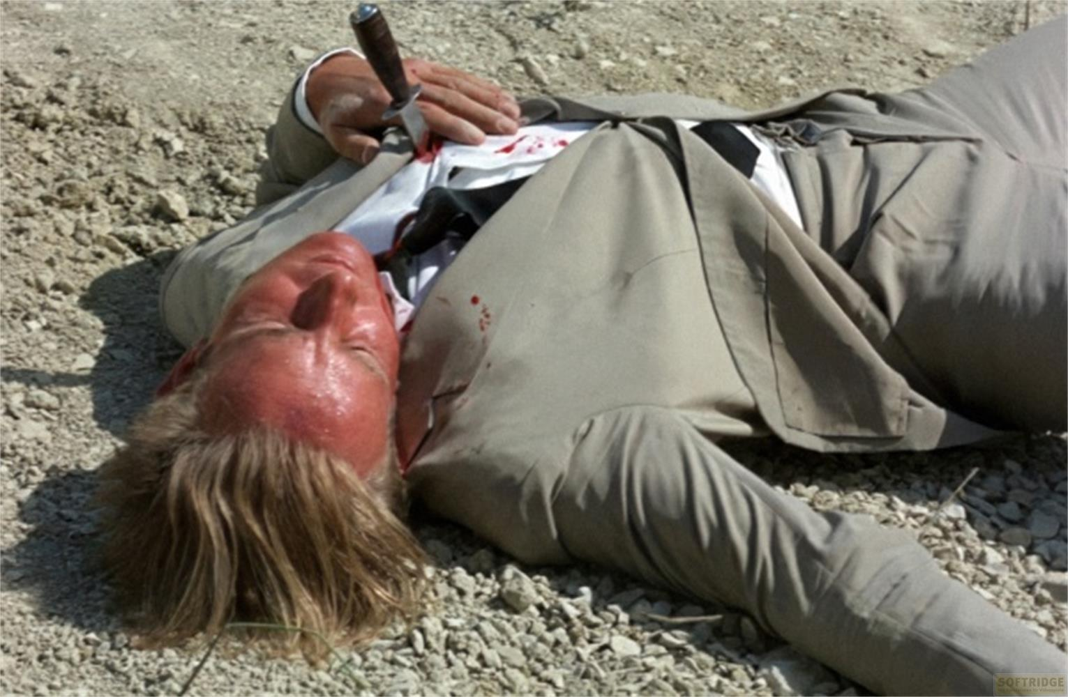 Un uomo in abito giace morto a terra, un coltello nel petto.