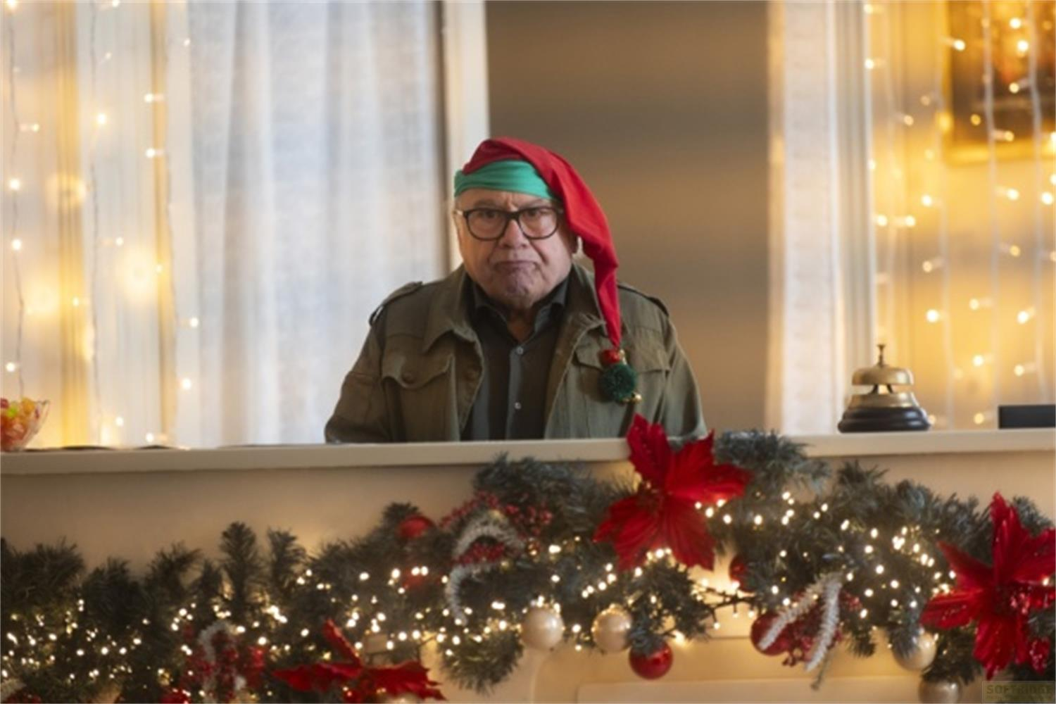 Ein Mann mit Weihnachtsmütze und Brille steht hinter einem geschmückten Tresen.