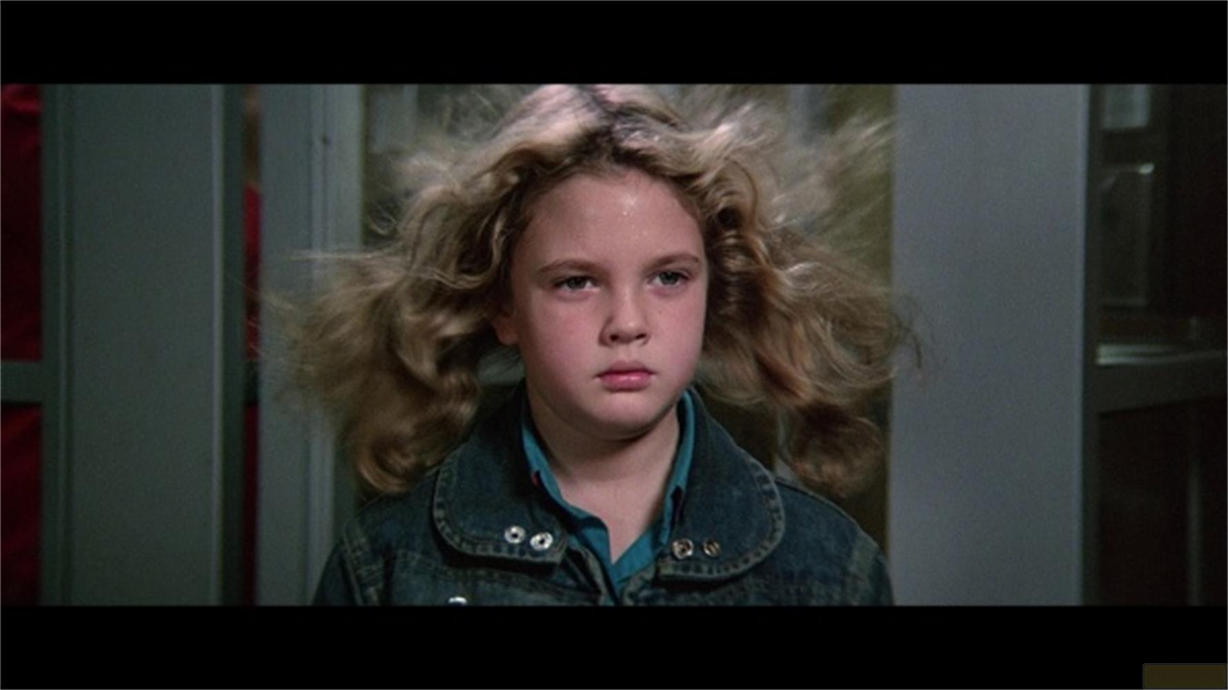 Una bambina con i capelli biondi mossi dal vento indossa una giacca di jeans.