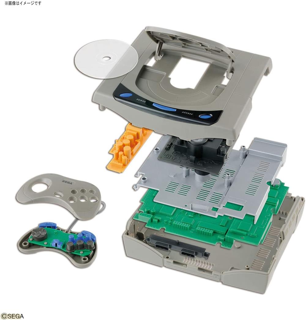 Zerlegte Spielkonsole mit Controller und CD. Innenleben mit grünen Platinen sichtbar.