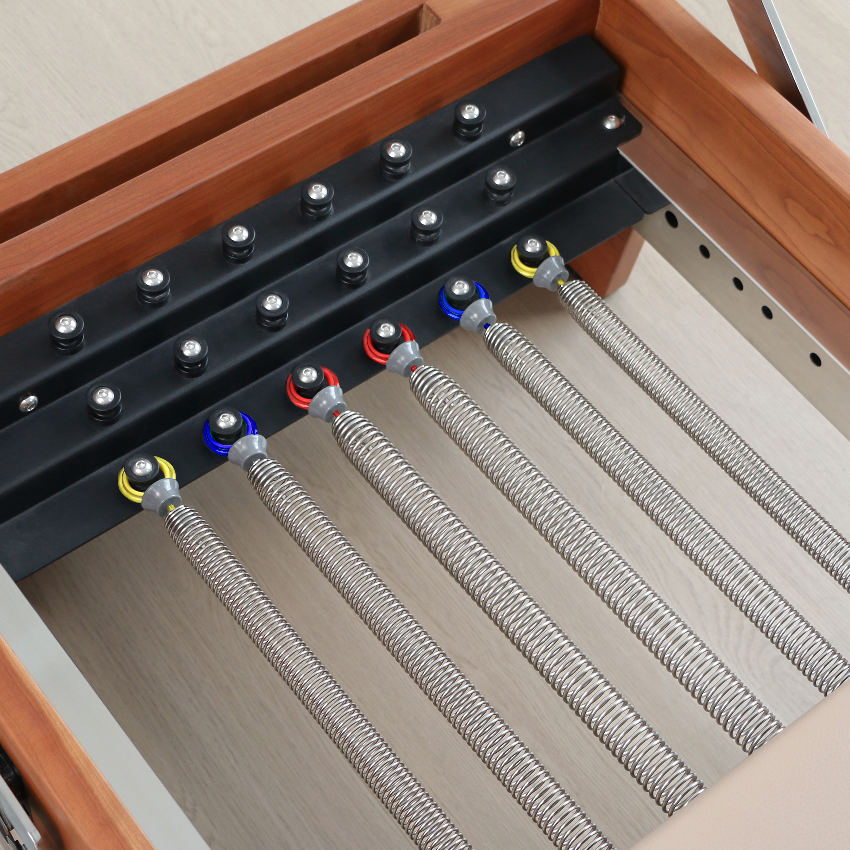 Molle Reformer Pilates con estremità colorate su una guida nera.