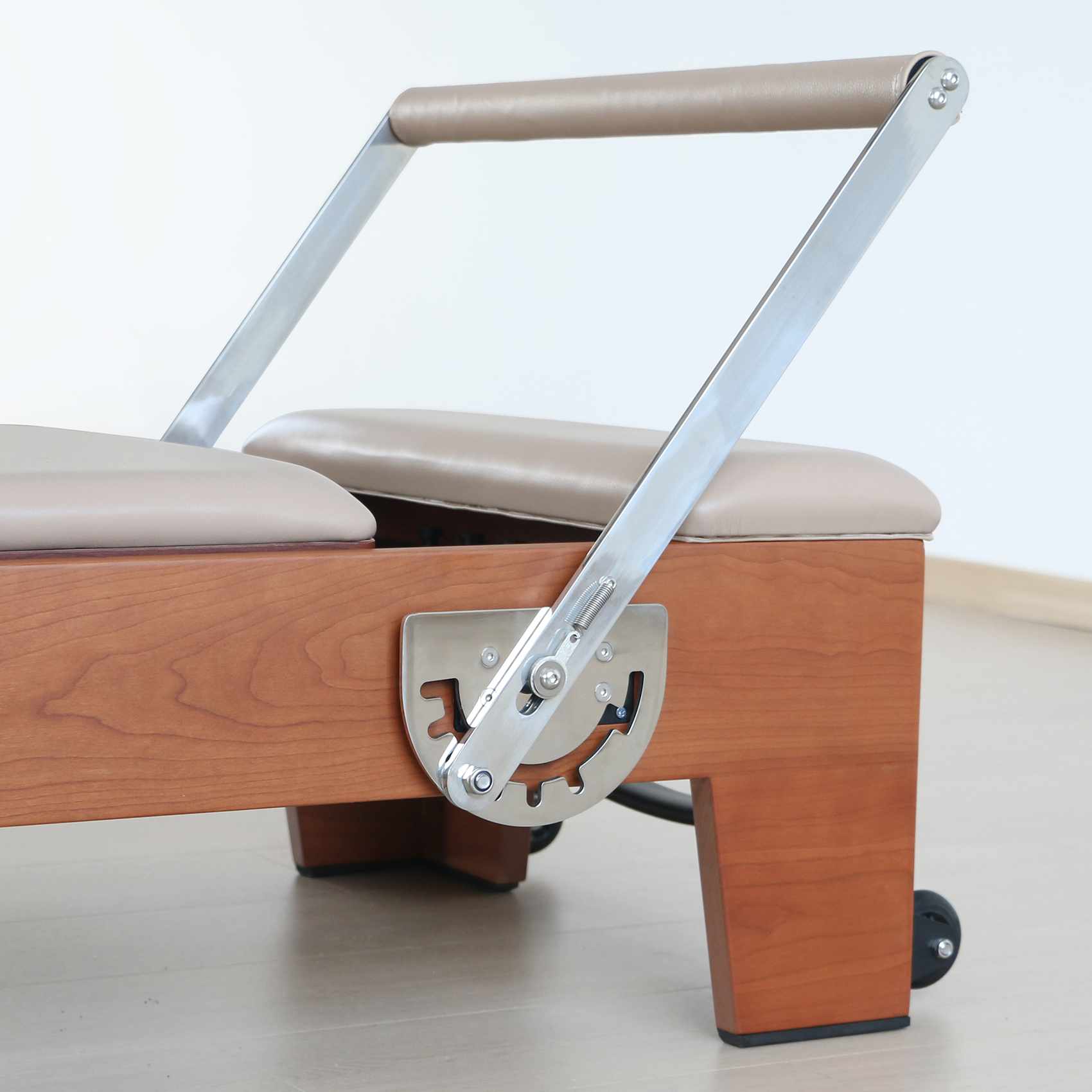 Un reformer Pilates in legno con parti metalliche e sedili imbottiti.