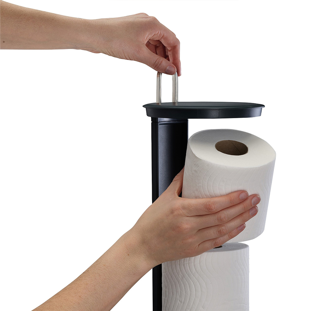 Una persona coloca un rollo de papel higiénico en un soporte negro con dos rollos.