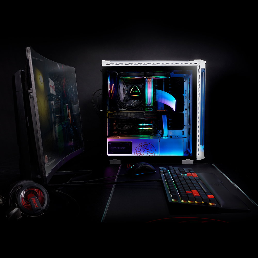 Un PC da gaming con illuminazione RGB accanto a un monitor curvo.