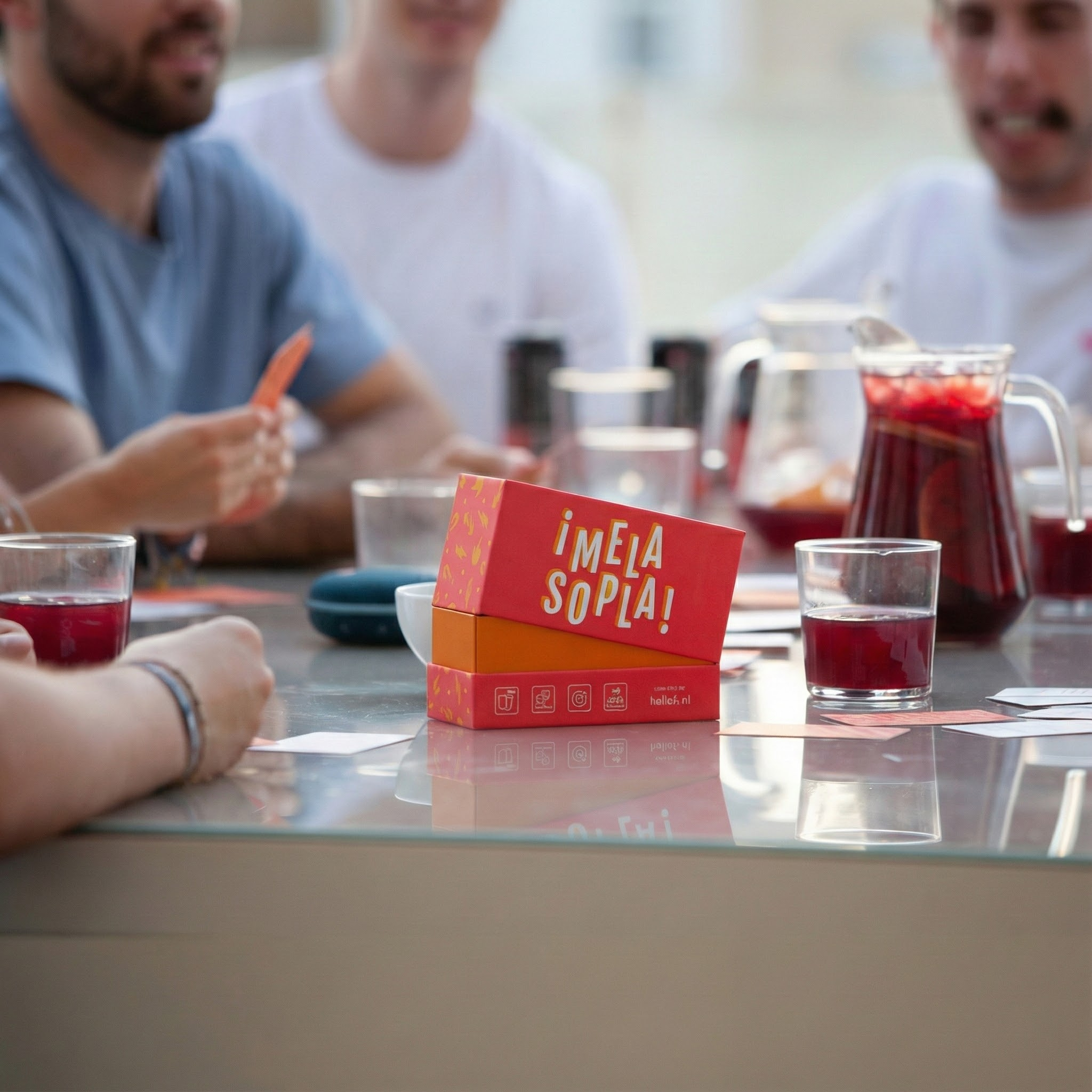Personas jugando a un juego de cartas con bebidas y una jarra sobre una mesa.