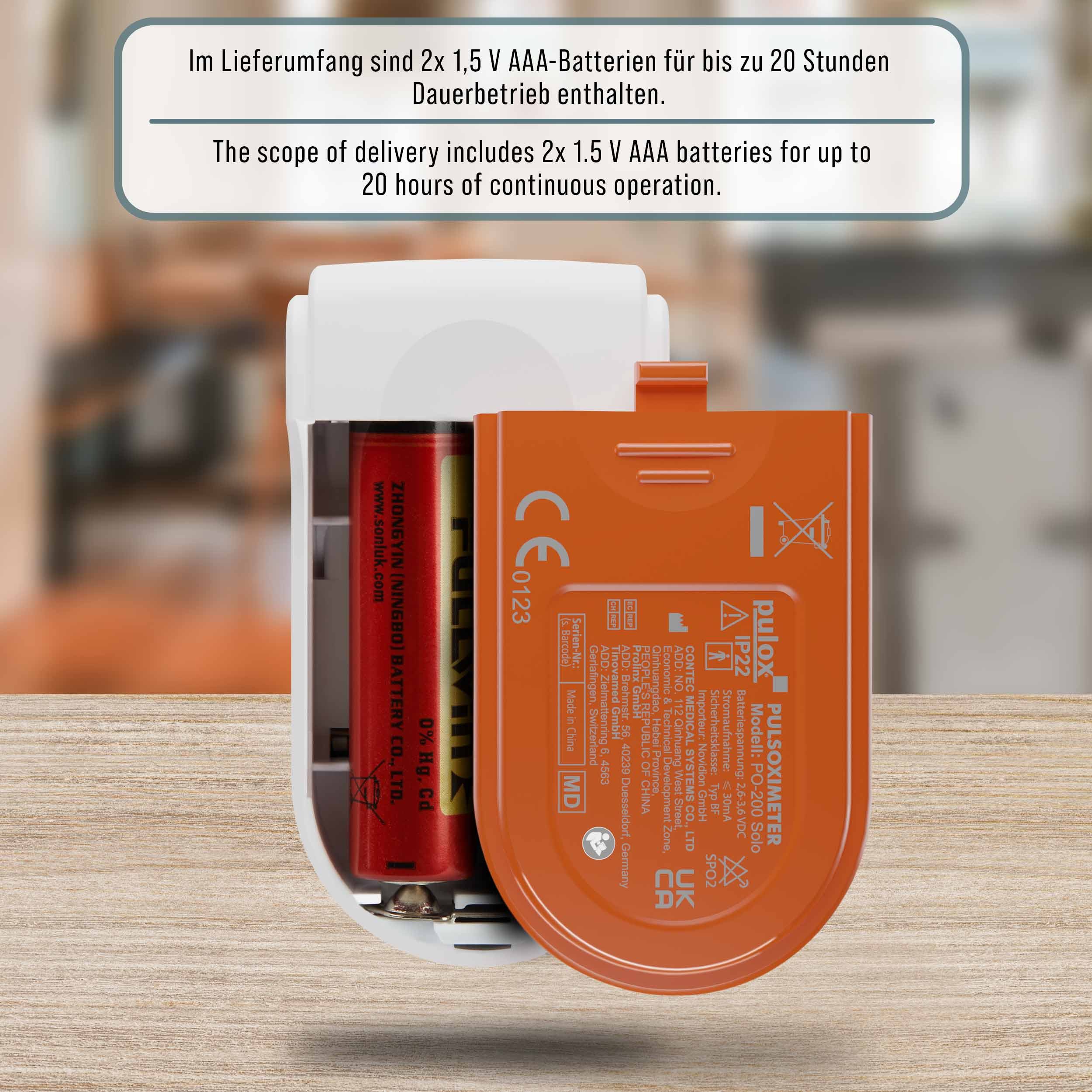 Ein Pulsoximeter mit AAA-Batterie und CE-Kennzeichnung auf einem Holztisch.