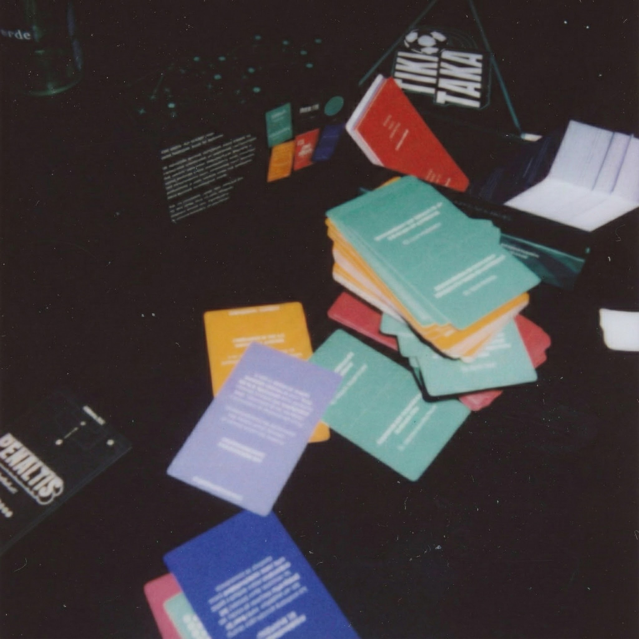 Pilas de libros y tarjetas en varios colores sobre una mesa oscura.