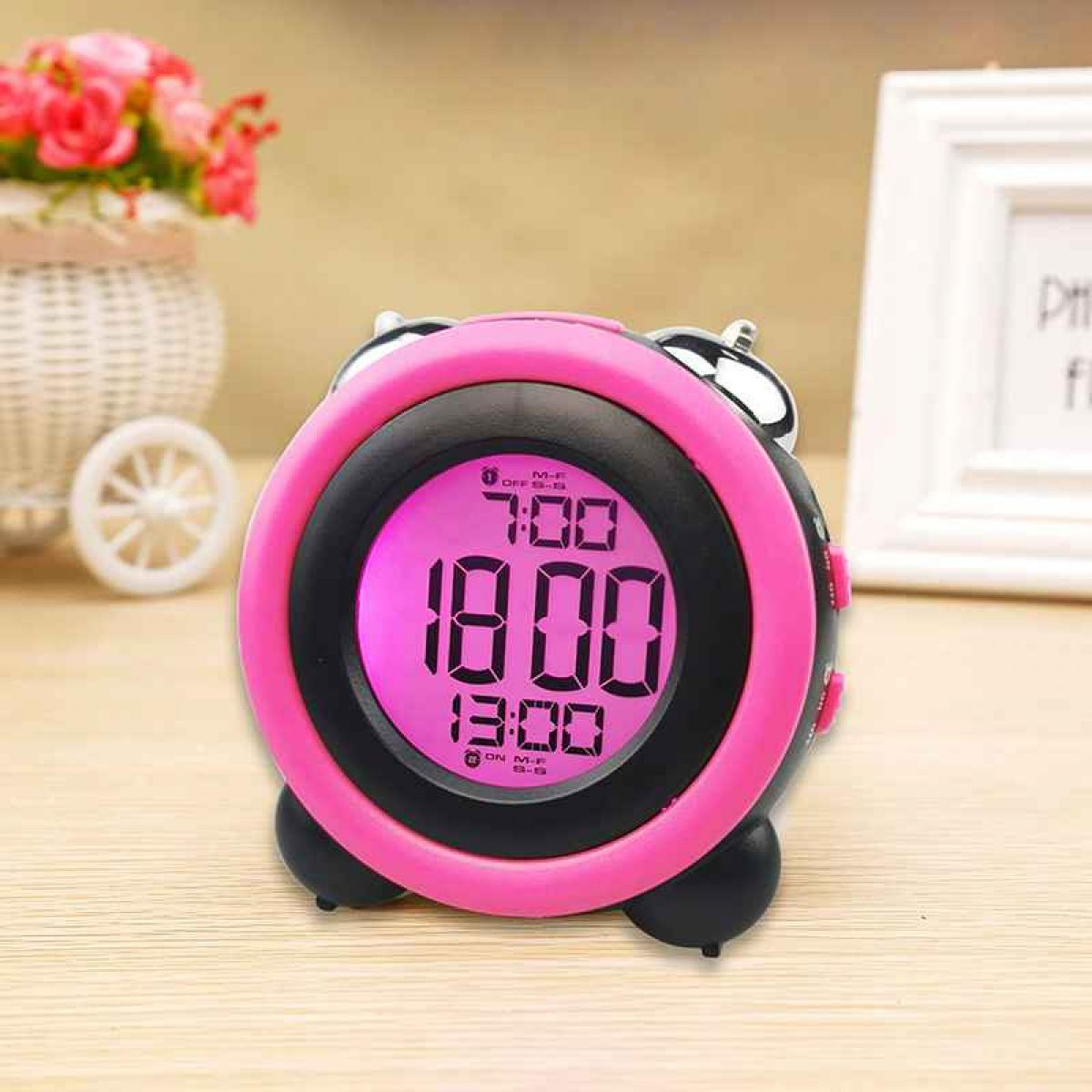 Ein pinker Digitalwecker mit leuchtendem Display steht auf einem Holztisch.