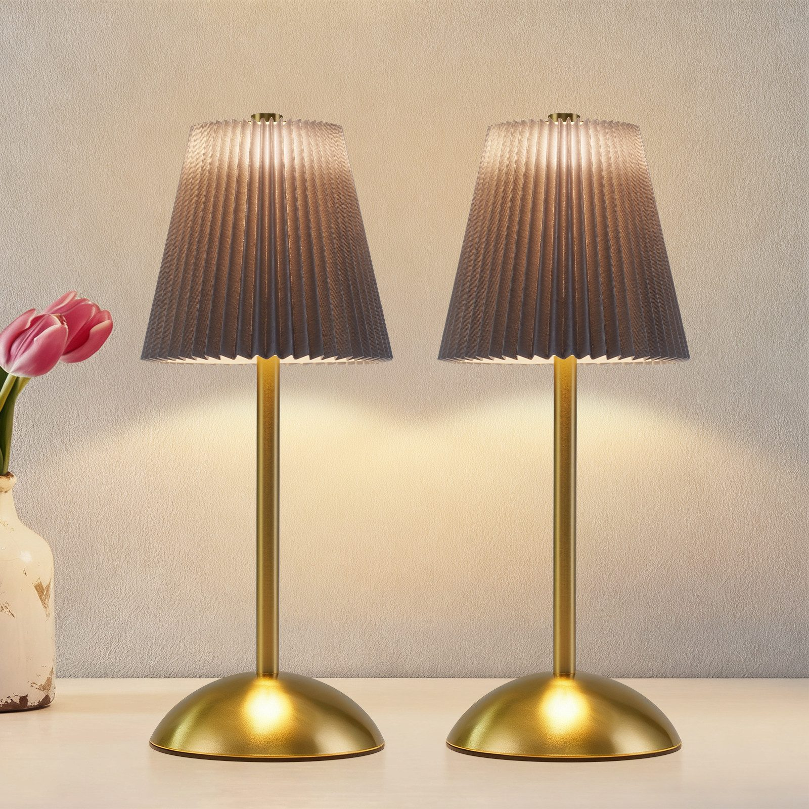 Due lampade da tavolo con paralumi grigi plissettati e steli dorati.