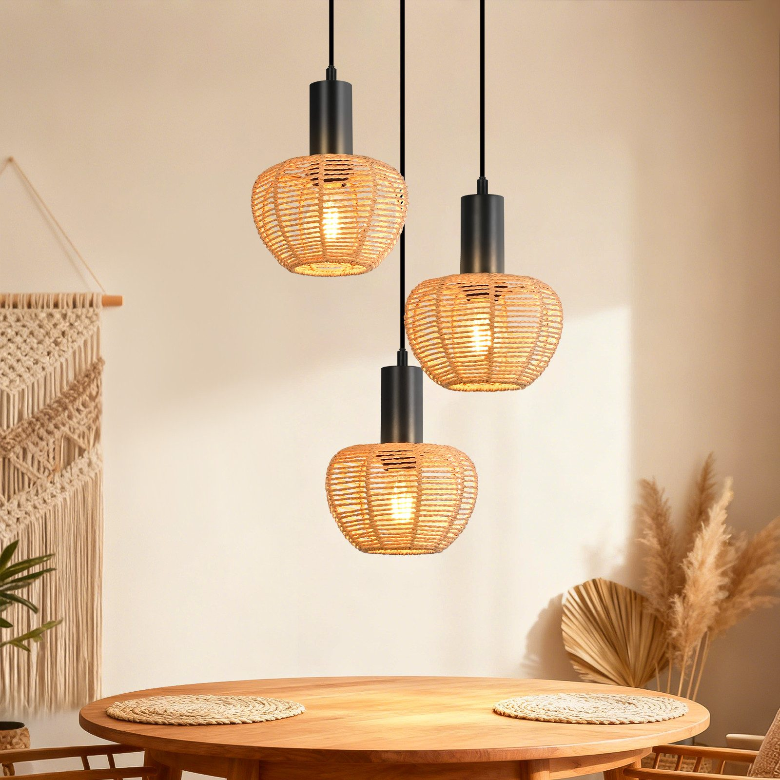 Tre lampade a sospensione in rattan pendono su un tavolo di legno con sottobicchieri.