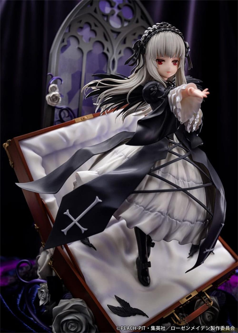 Eine Figur eines Mädchens in einem schwarzen Kleid mit weißen Rüschen, das aus einem Sarg aufsteigt.