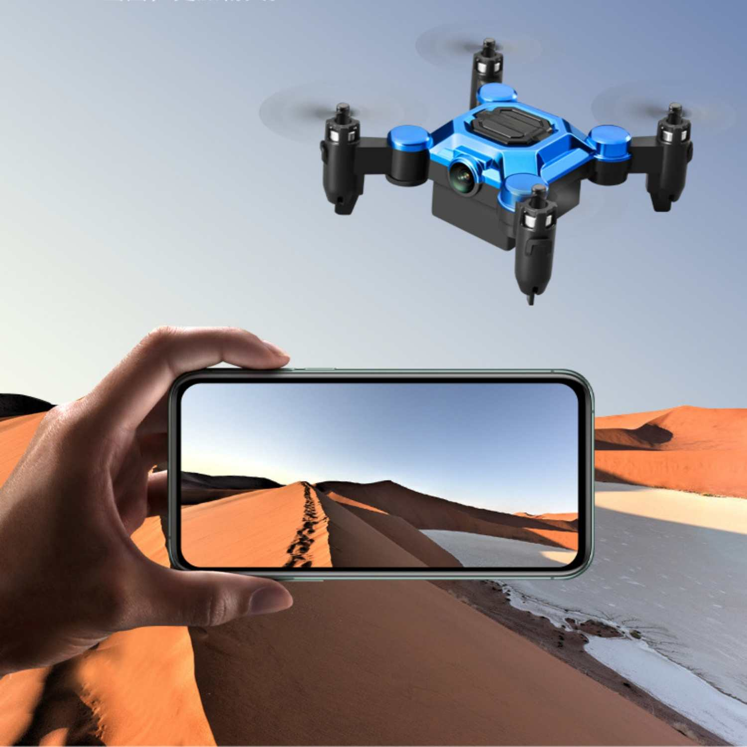 Ein blauer und schwarzer Quadrocopter fliegt über eine Wüstenlandschaft, die auf einem Handybildschirm zu sehen ist.