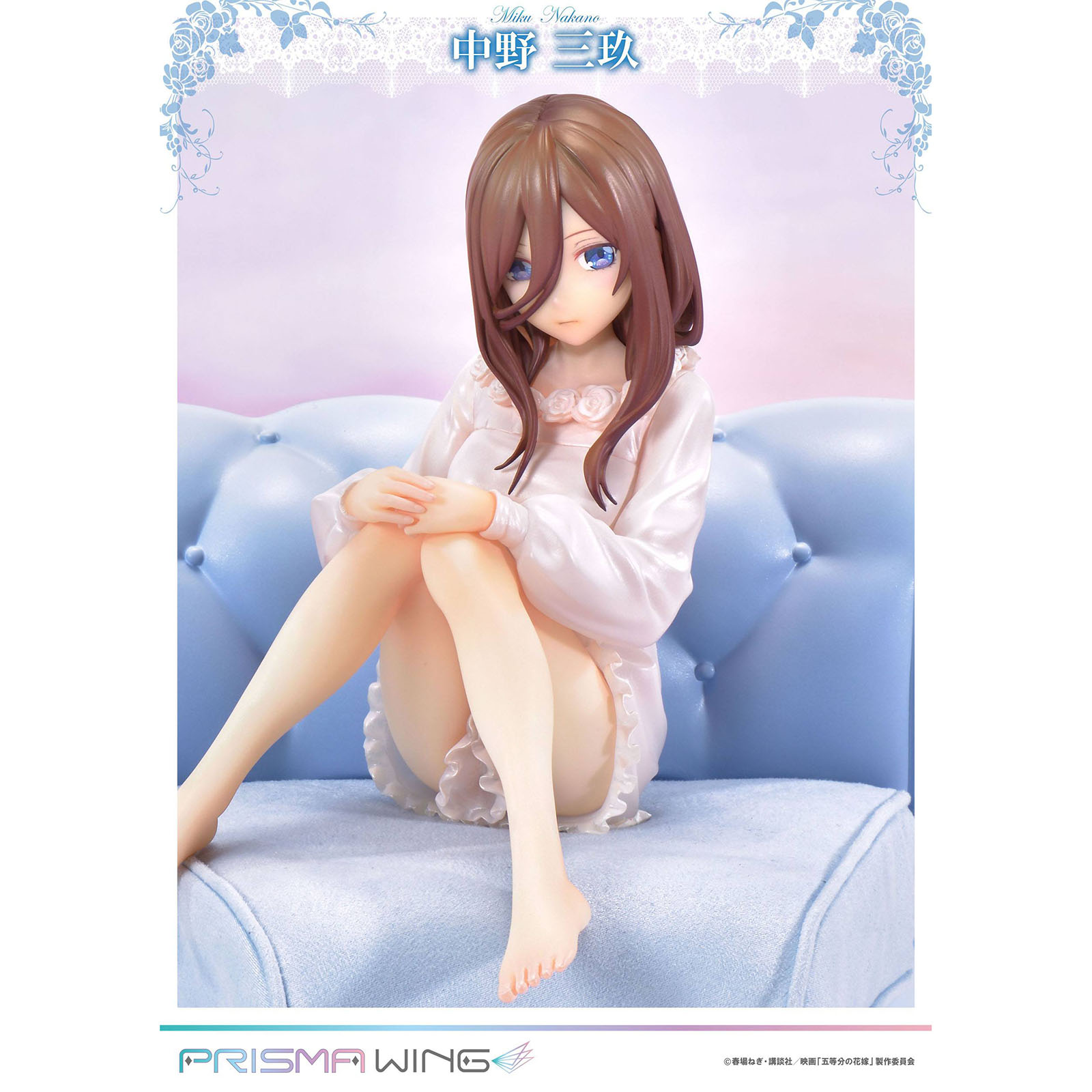 Eine Figur von Miku Nakano sitzt auf einem blauen Sofa, trägt ein weißes Kleid.