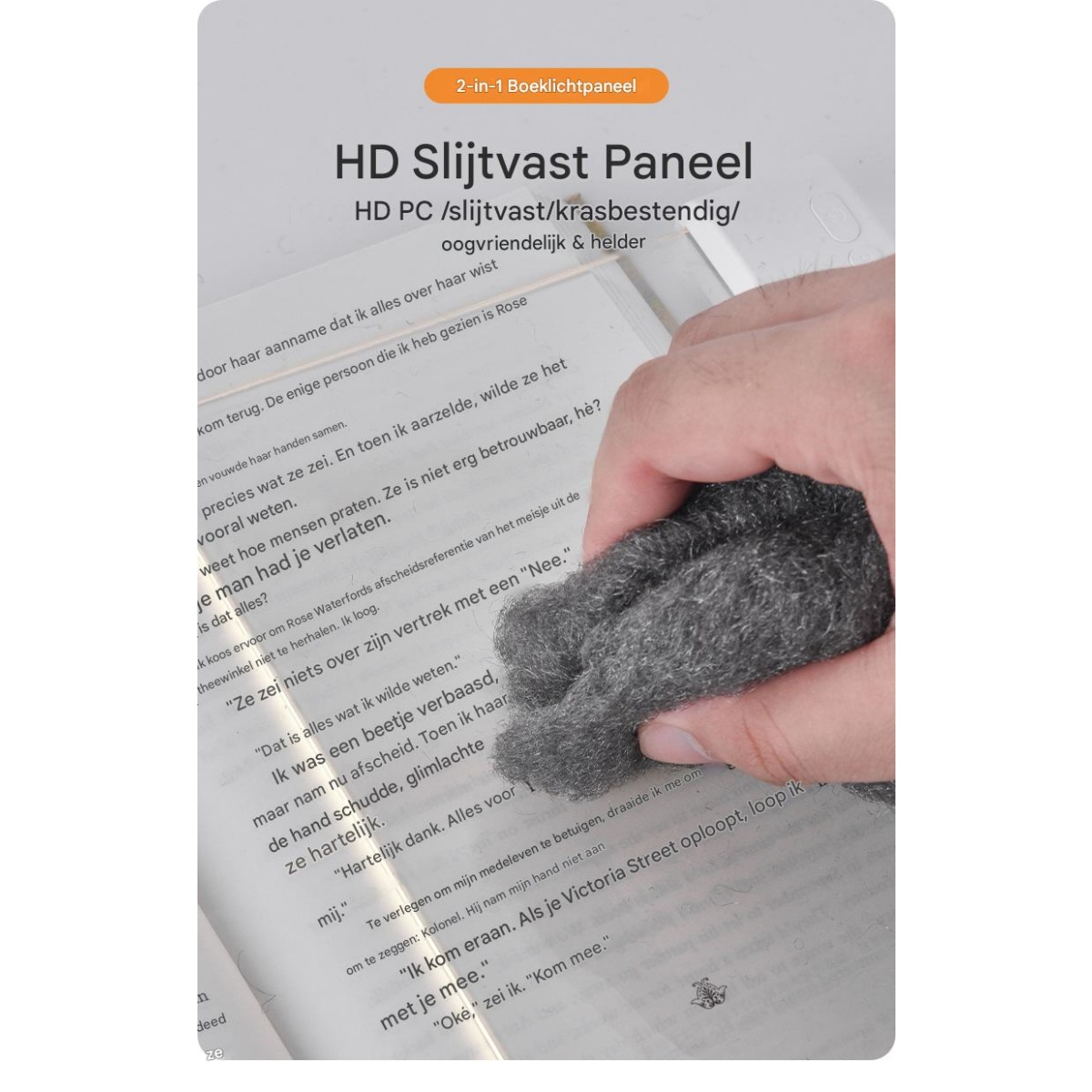 Eine Hand zerknüllt Stahlwolle über einem Buch mit niederländischem Text.