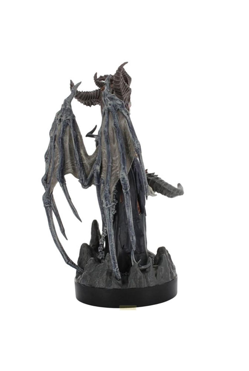 Figurine sombre avec ailes et cornes sur socle rocheux.