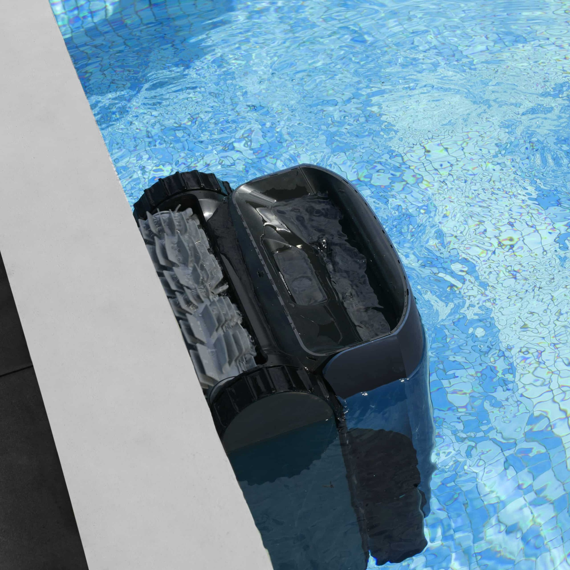 Ein schwarzer Poolroboter mit Rädern schwimmt im blauen Wasser eines Pools.