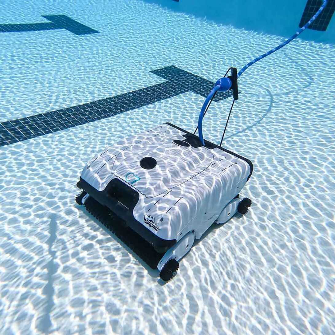 Un limpiador de piscina blanco con cable azul flota en agua clara.