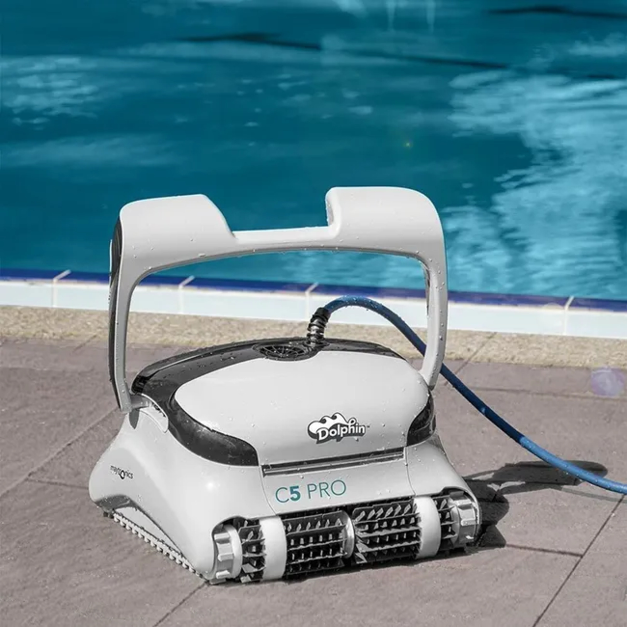 Un limpiafondos blanco con manguera azul junto al borde de una piscina.