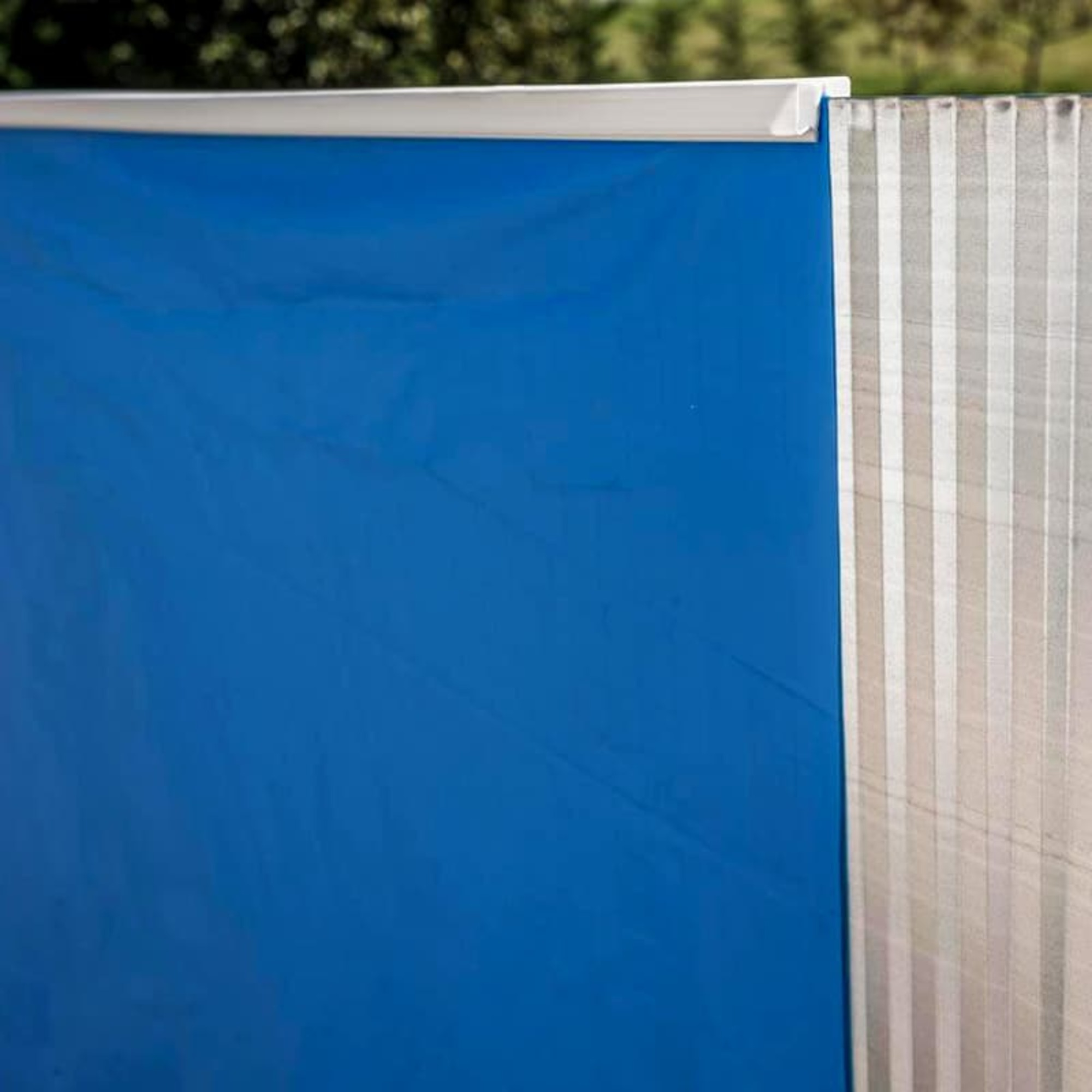 Lona azul con borde blanco, junto a una pared a rayas.