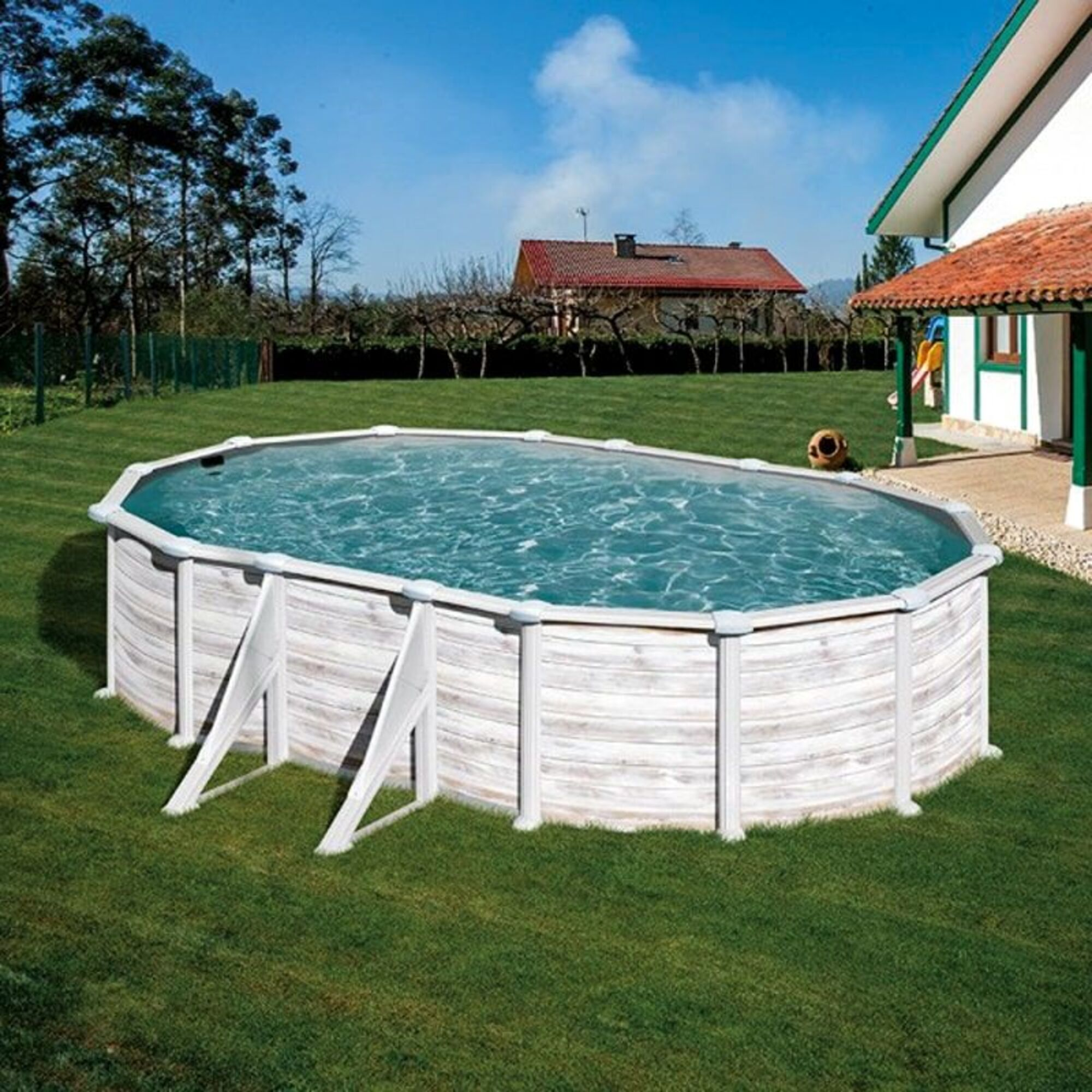 Una piscina ovalada de aspecto de madera se encuentra en el jardín junto a una casa.
