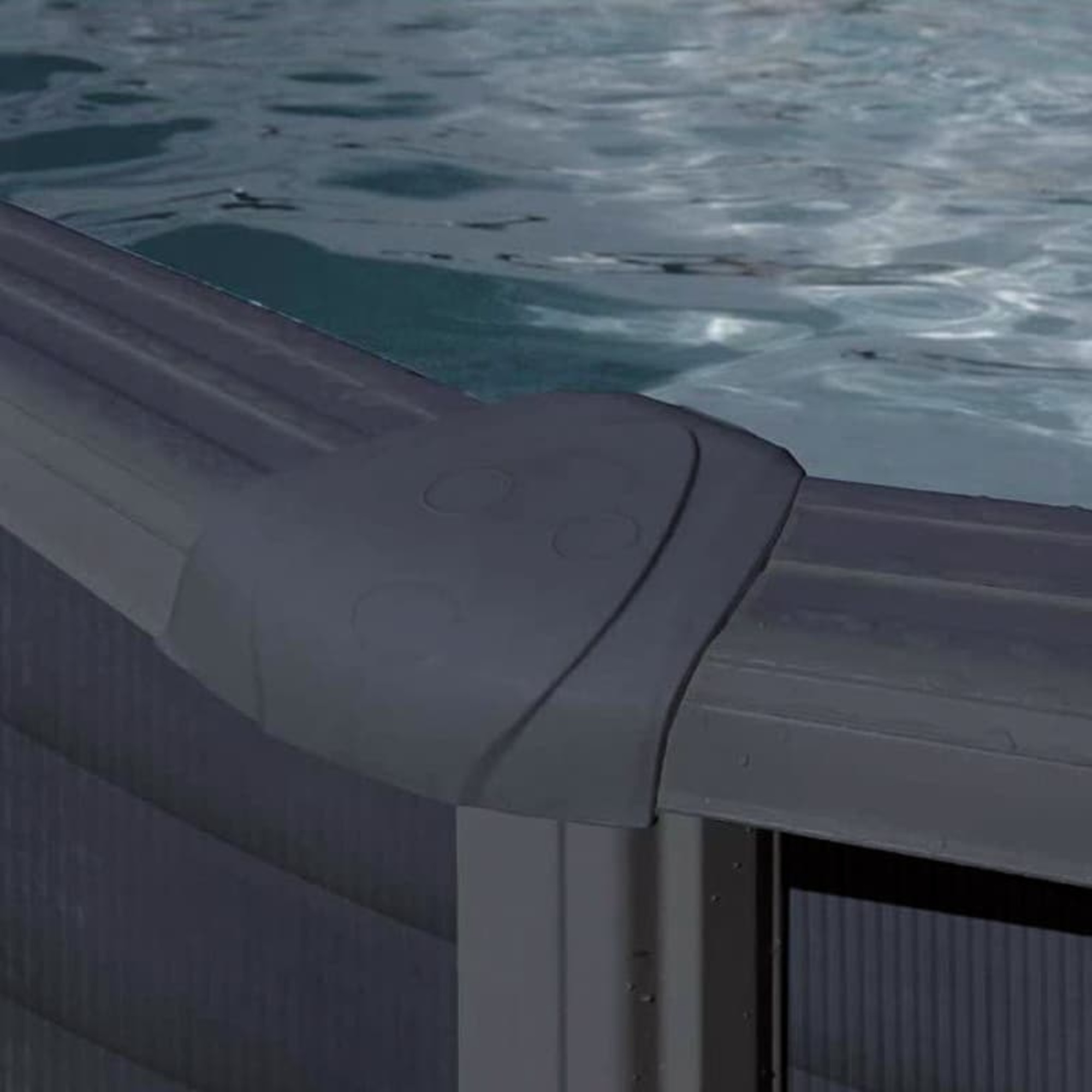 Borde de piscina gris oscuro con ondas en el agua.