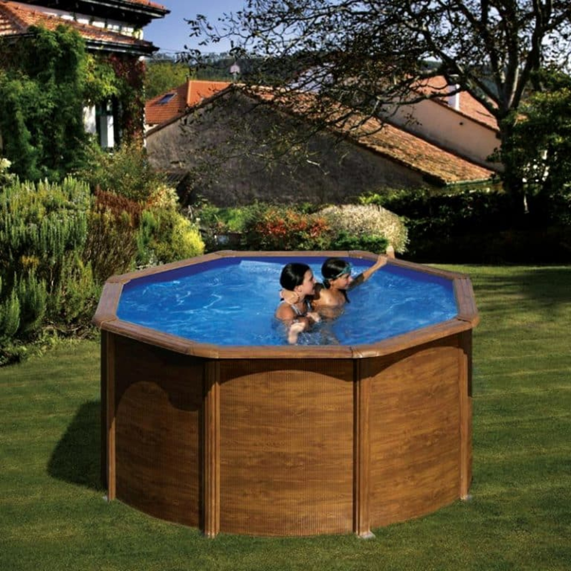 Dos niños chapotean en una piscina octogonal en un patio.