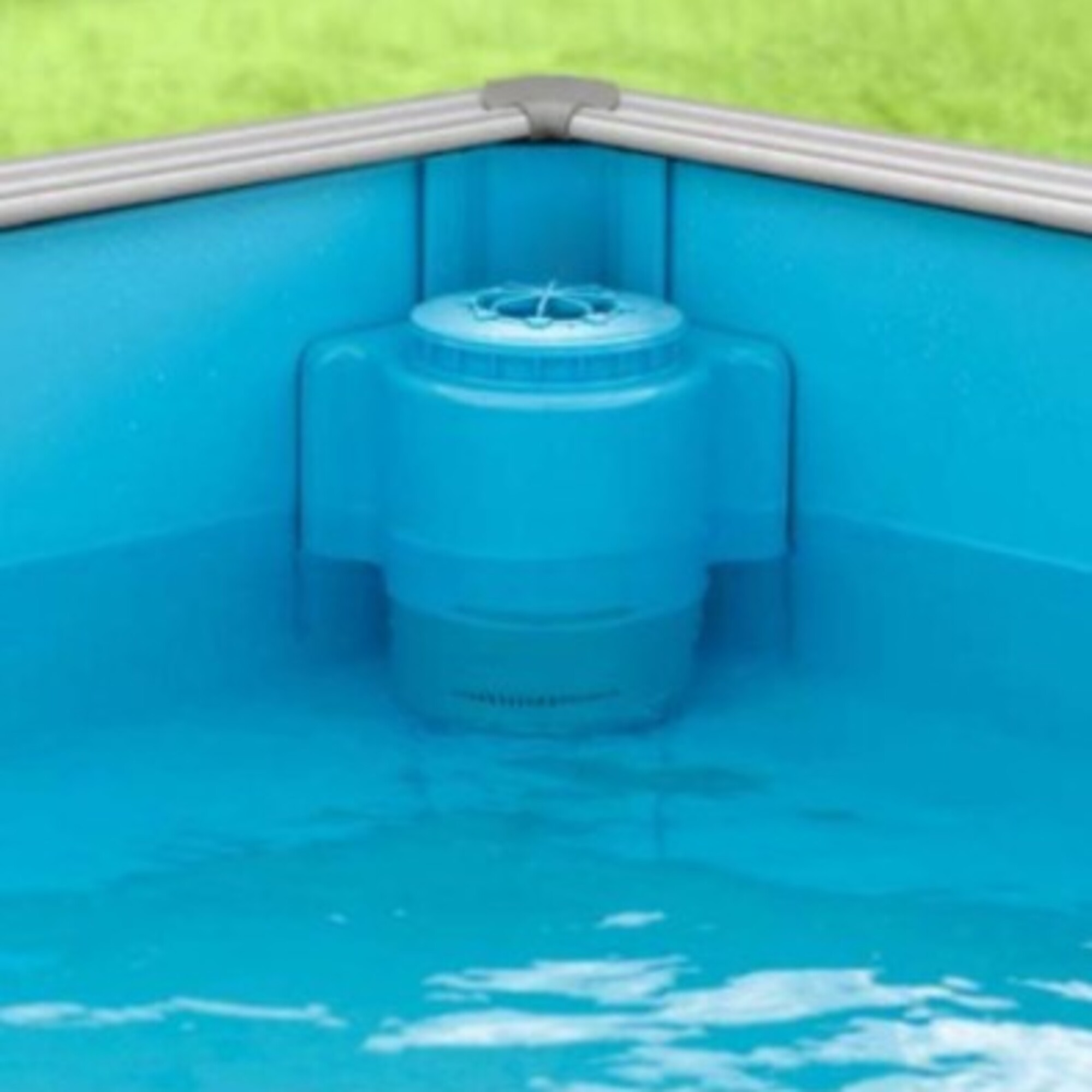Un skimmer azul con filtro en una piscina, con césped al fondo.