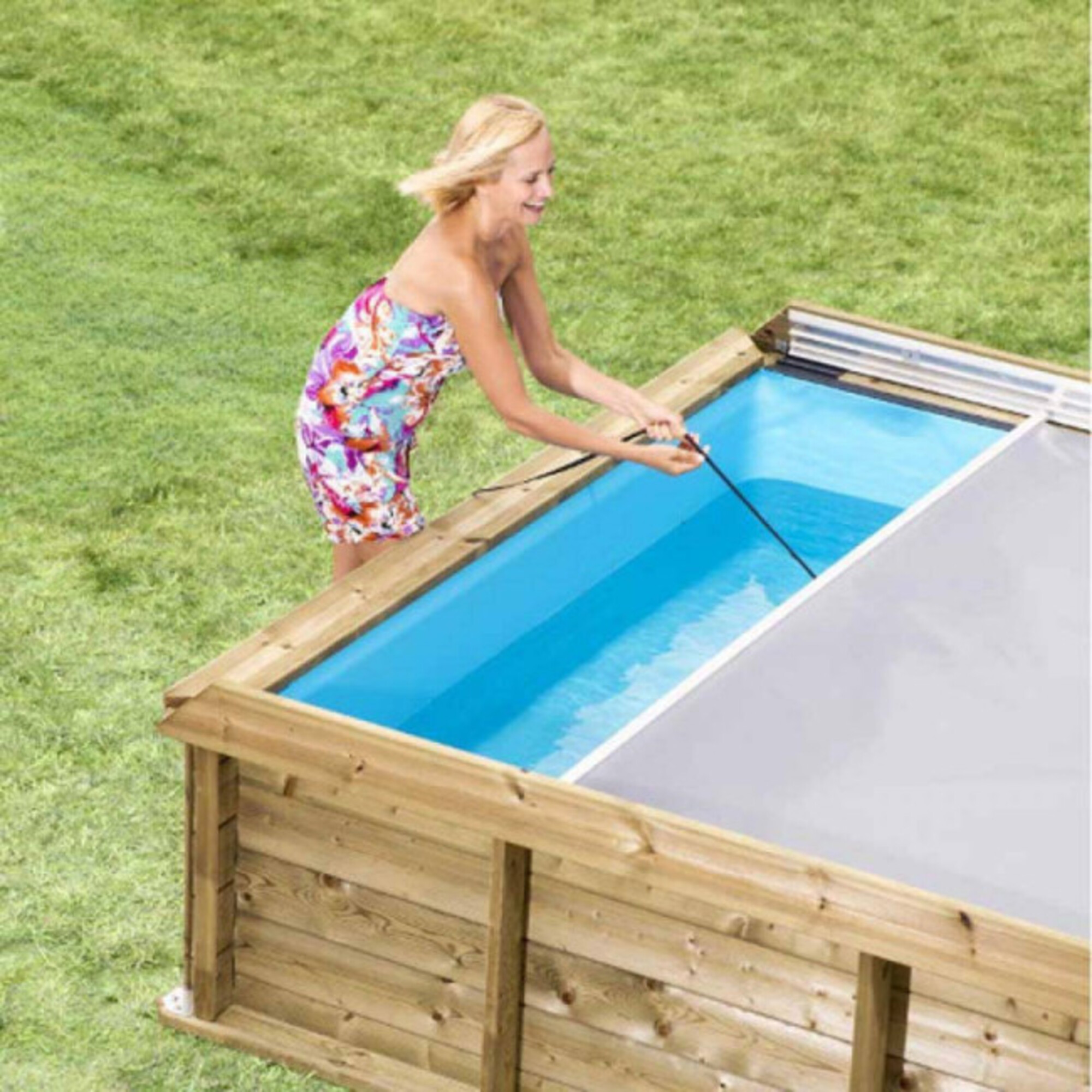Una mujer con un vestido colorido saca agua de una piscina de madera.