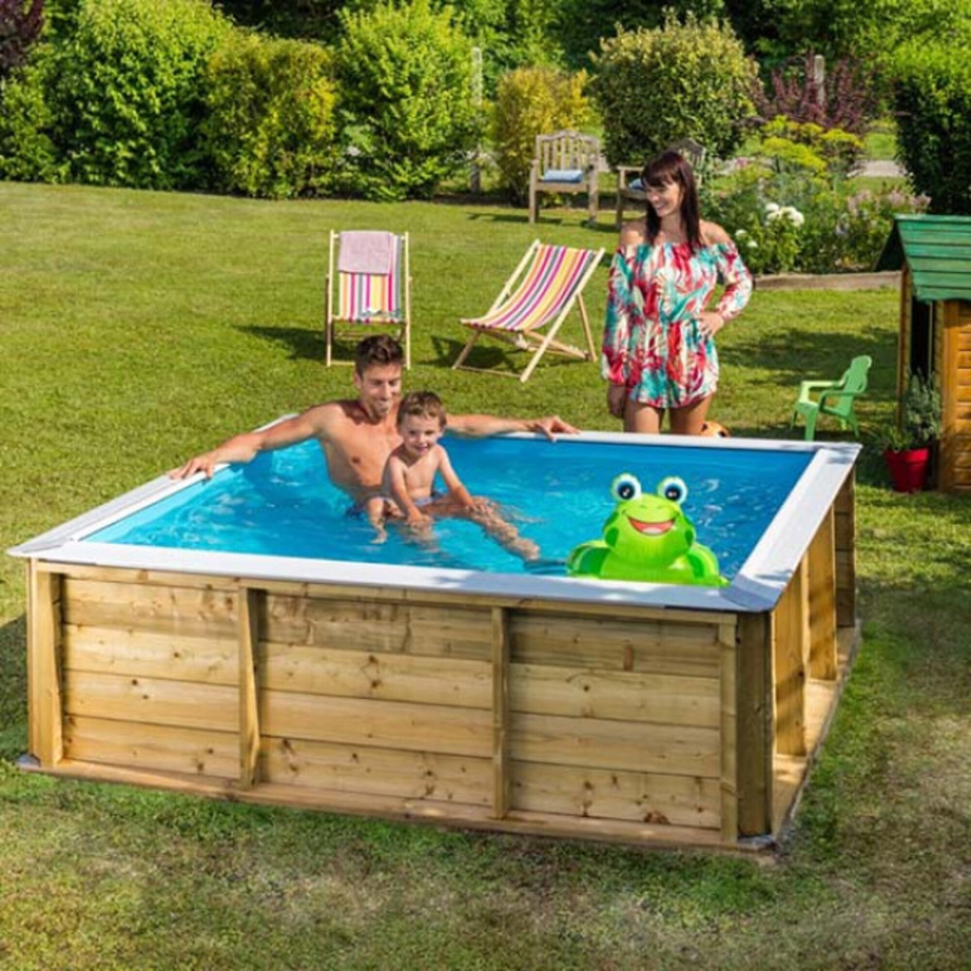 Familia en piscina de madera con flotador de rana y tumbonas en el jardín.