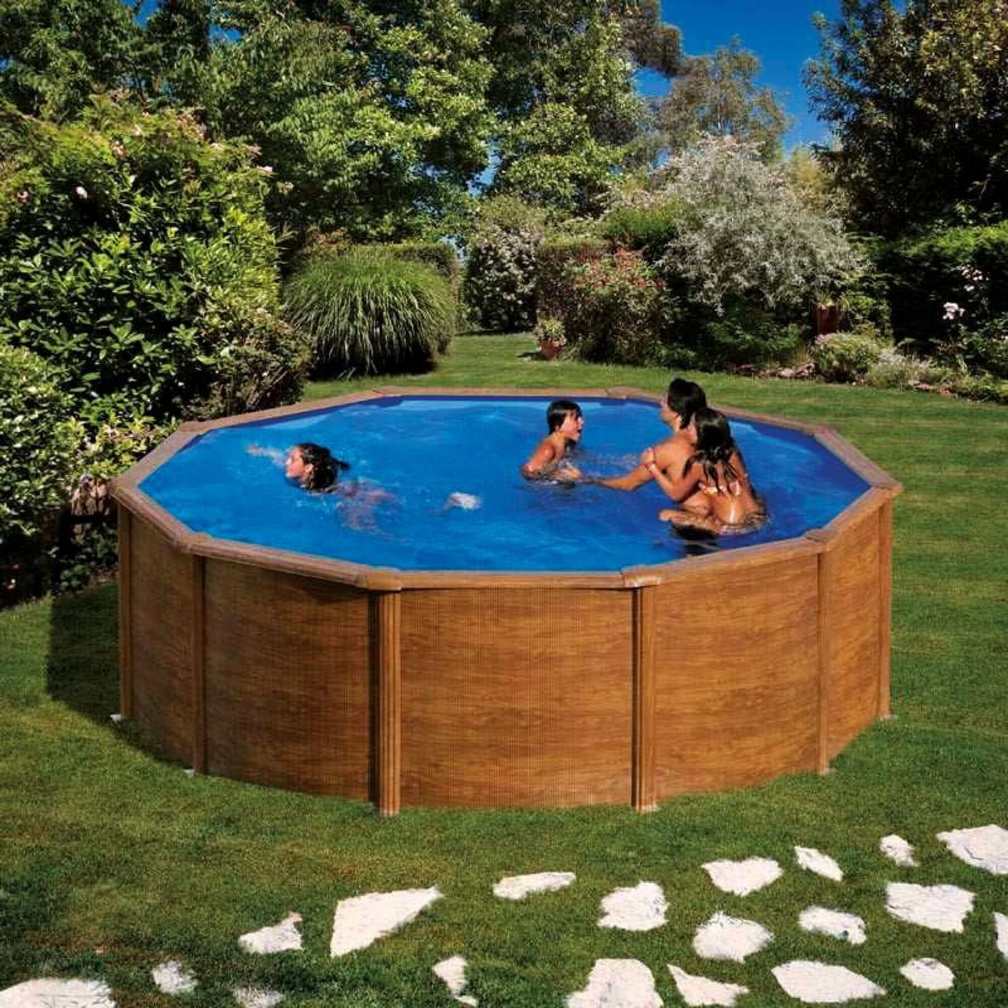 Niños chapotean en una piscina octogonal con revestimiento de madera en un jardín verde.