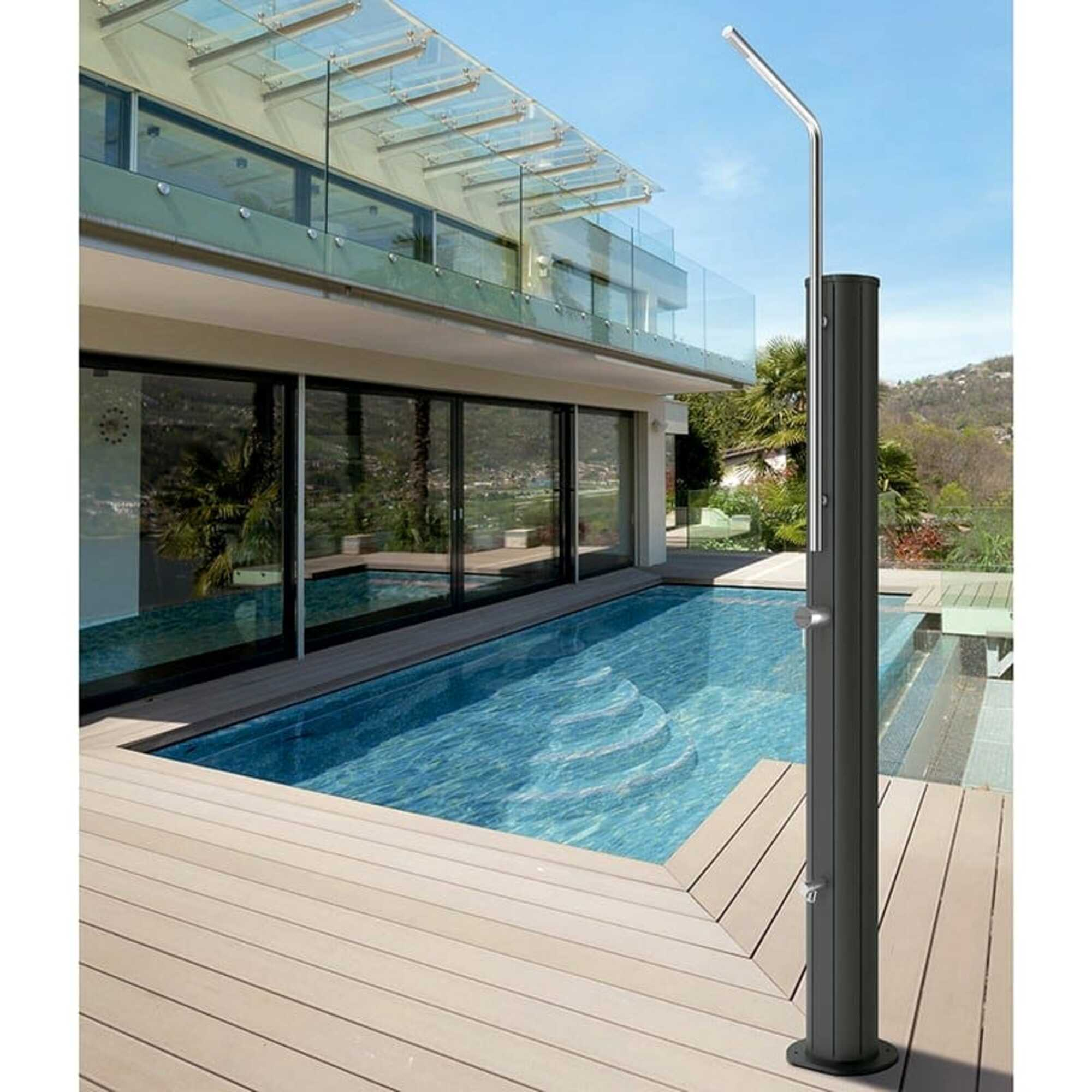 Una casa moderna con piscina y ducha exterior en un día soleado.